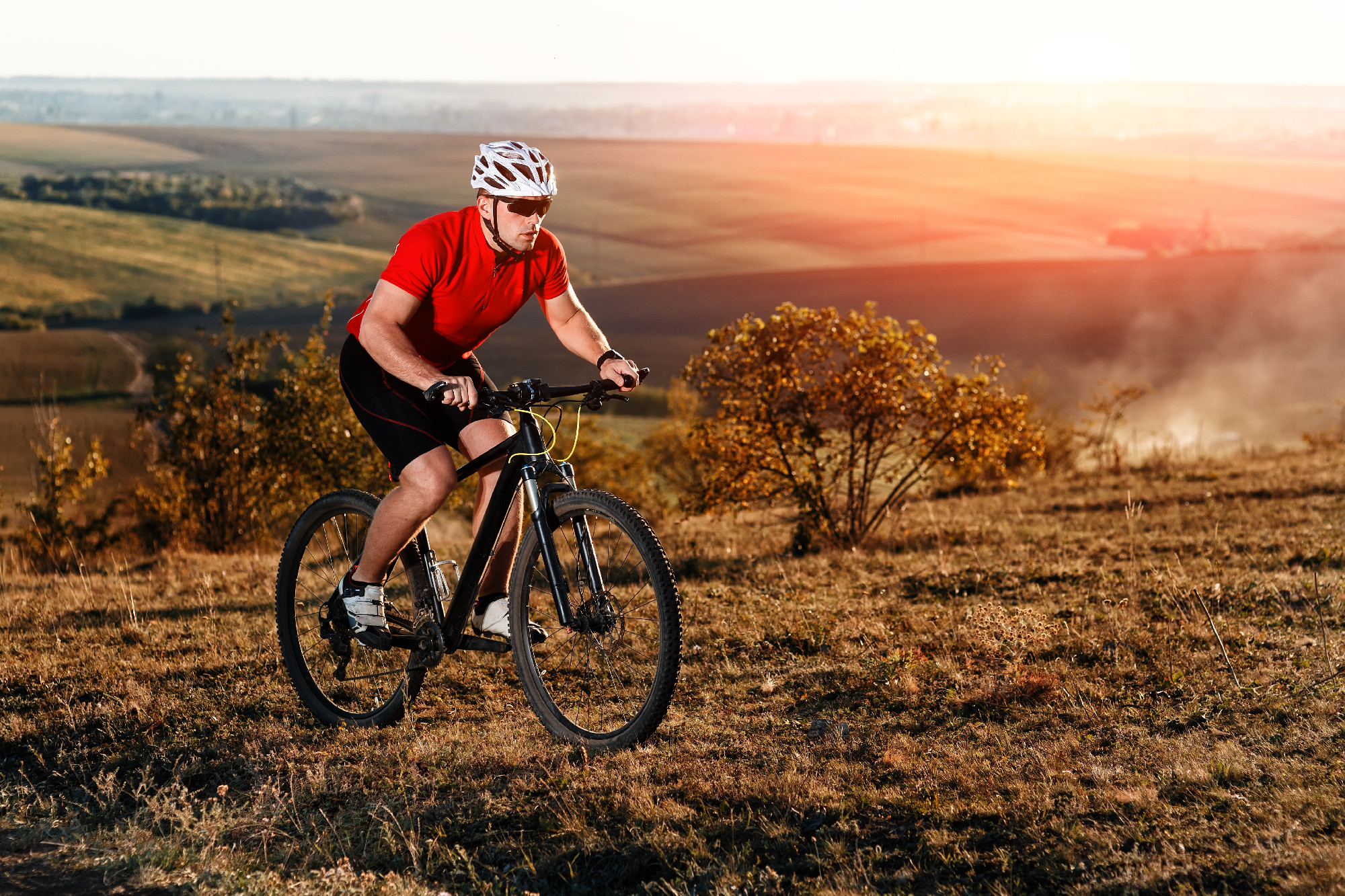 young bright man on mountain bike riding in autumn landscape