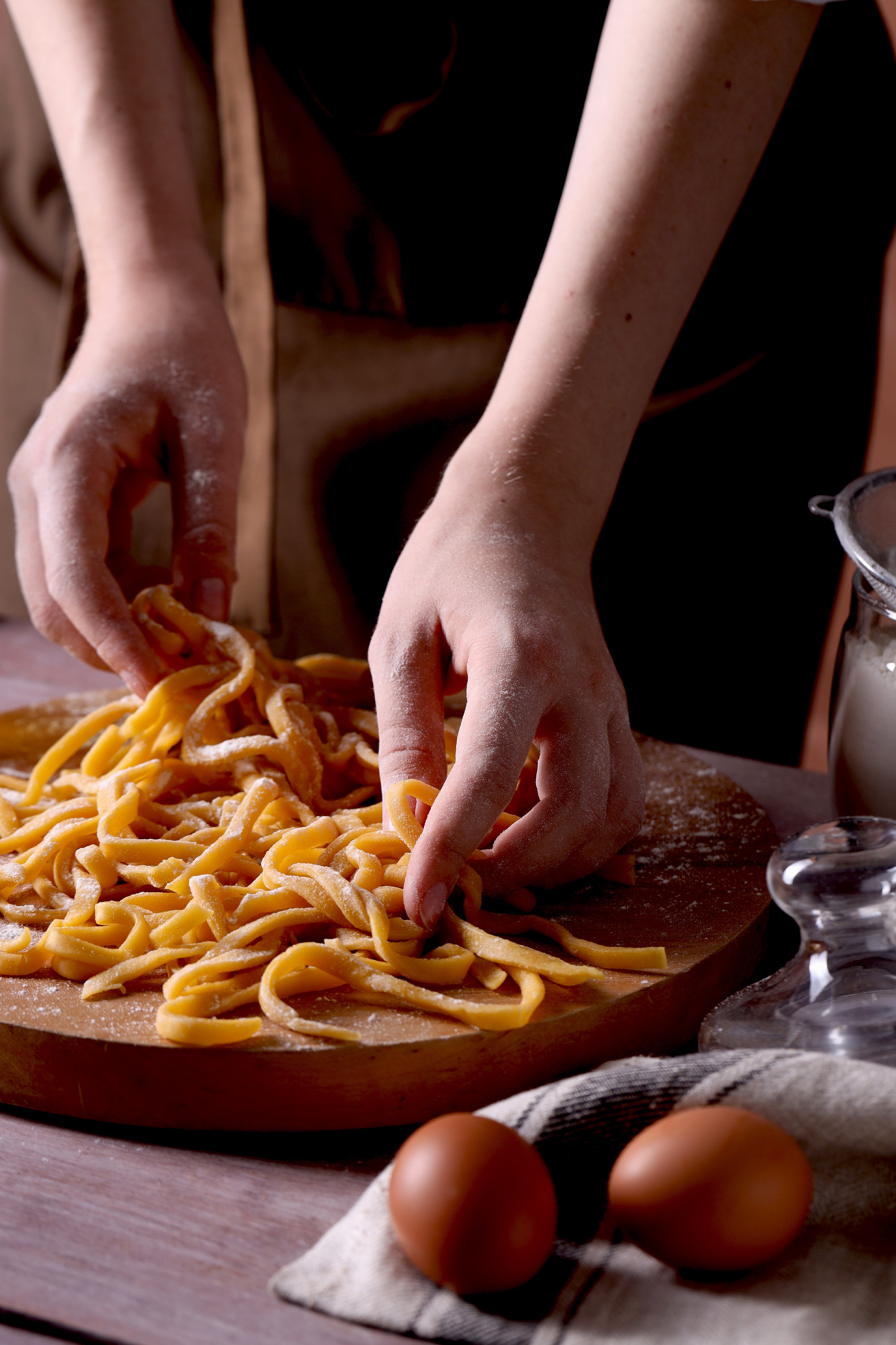 Woman making homemade pasta at wooden table, closeup