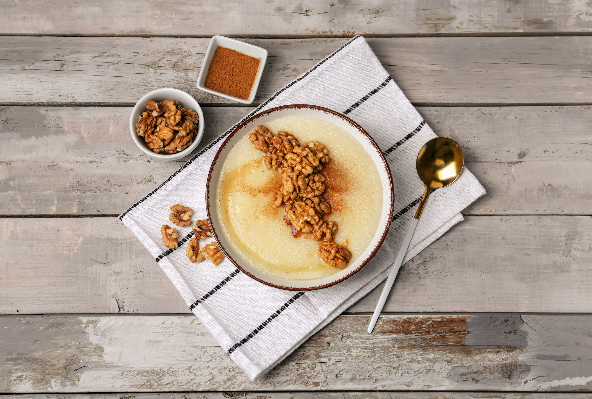Bowl of tasty semolina porridge with nuts on wooden background�
