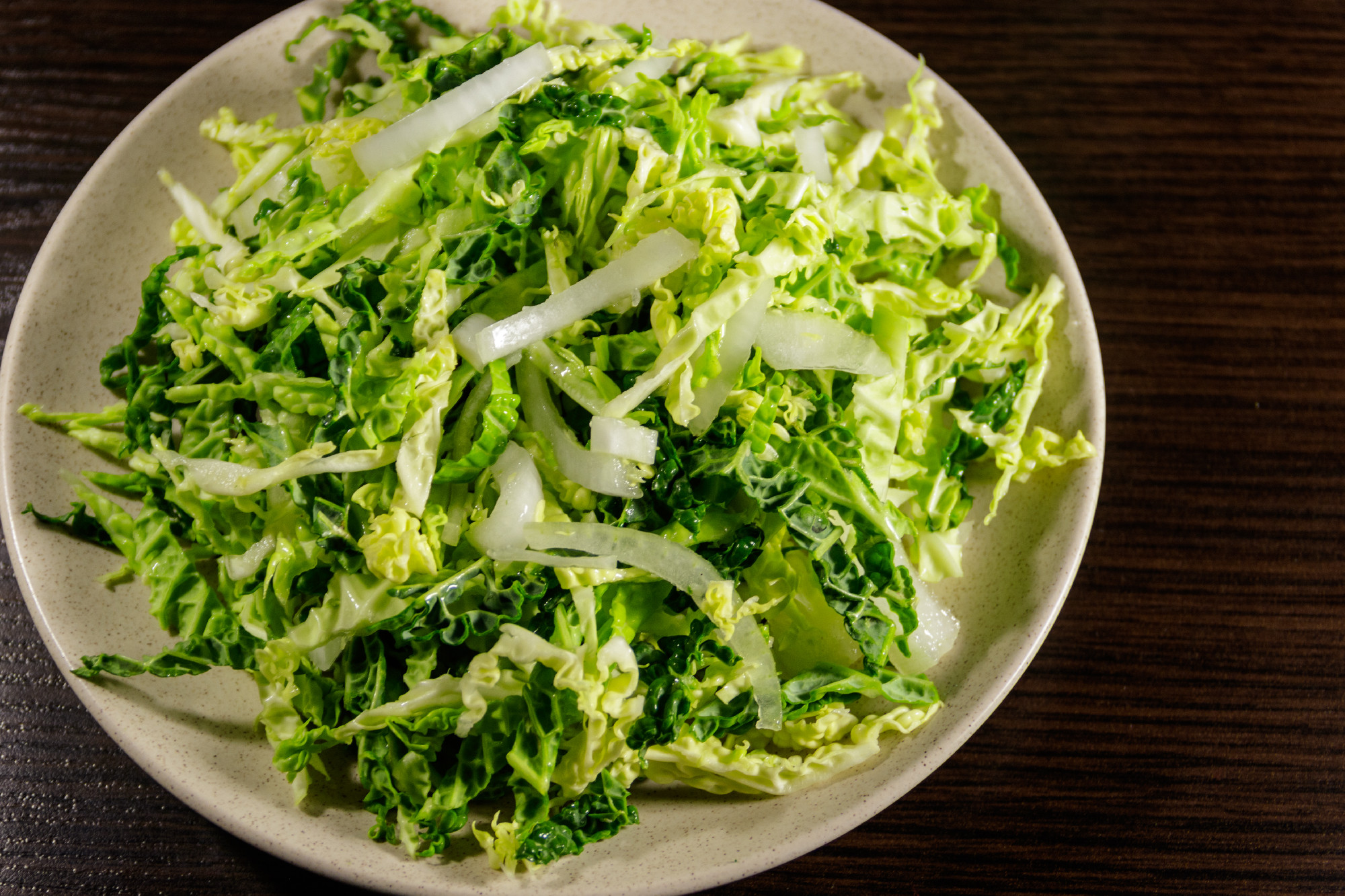 Salad with savoy cabbage and onion on wooden table