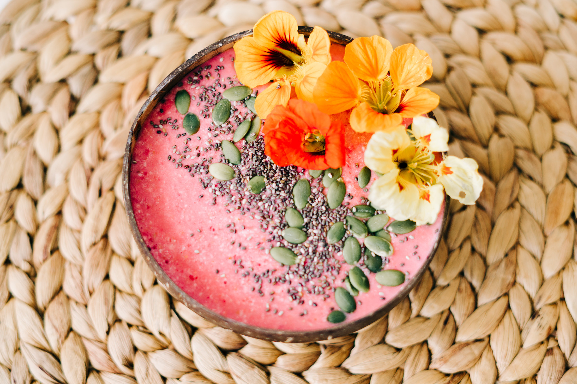 healthy Breakfast in a plate of coconut with nasturtium flowers on natural wicker napkin