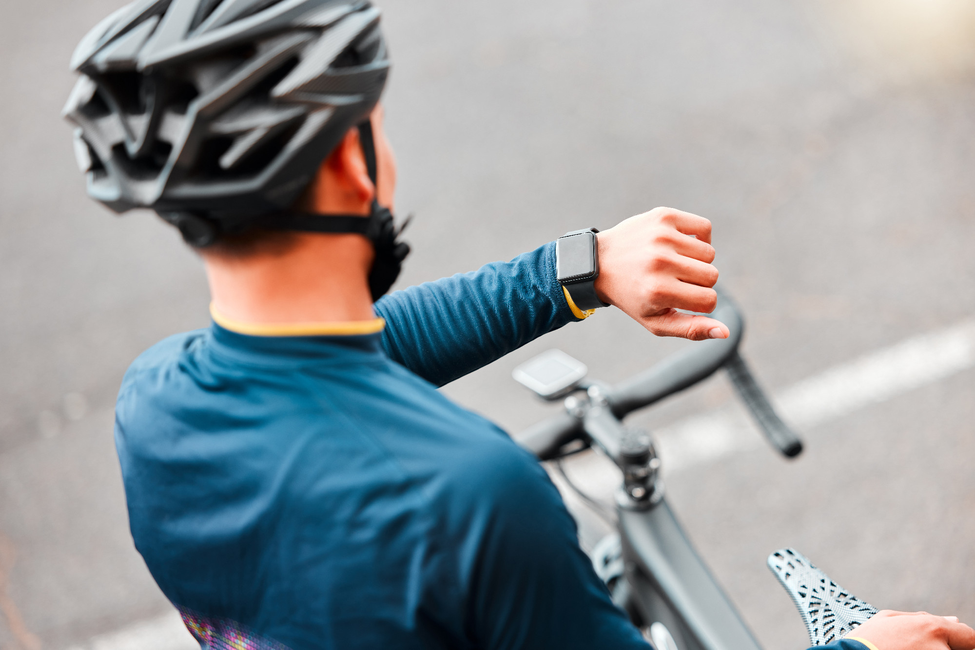 Watch, fitness and man cycling in the city on a bike for cardio health, exercise and sustainable lifestyle. Athlete cyclist training with the time on tech with a bicycle on the street for motivation