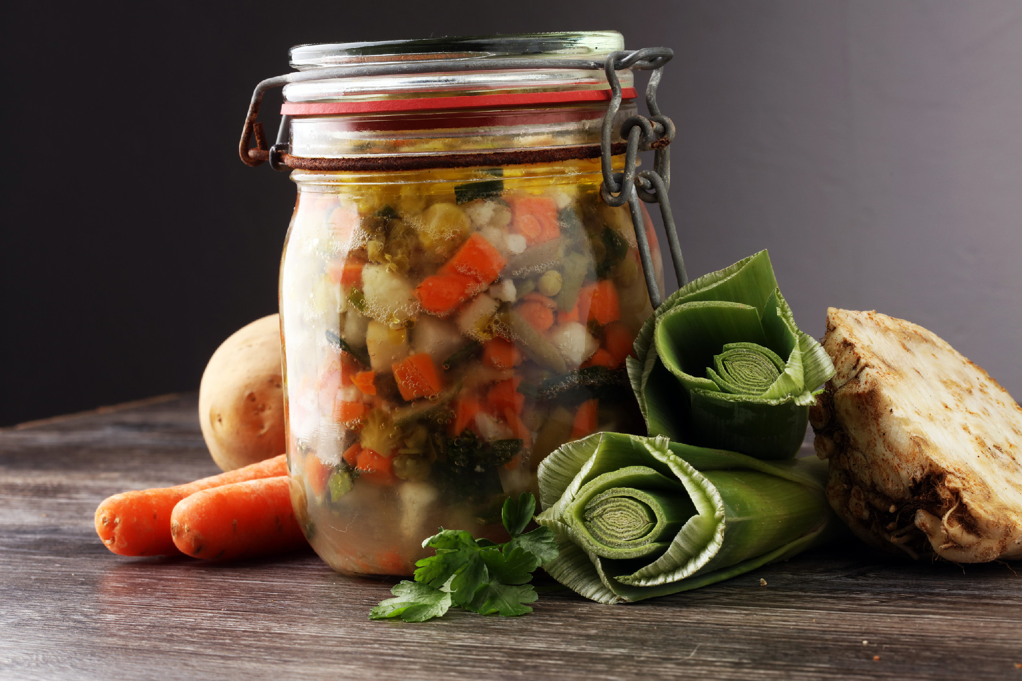Jar with variety of pickled vegetables. Carrots, field garlic, p