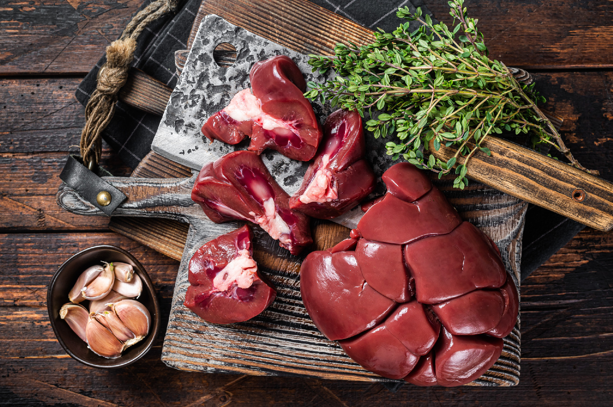 Raw lamb kidney, fresh offal meat on butcher board with herbs. Wooden background. Top view