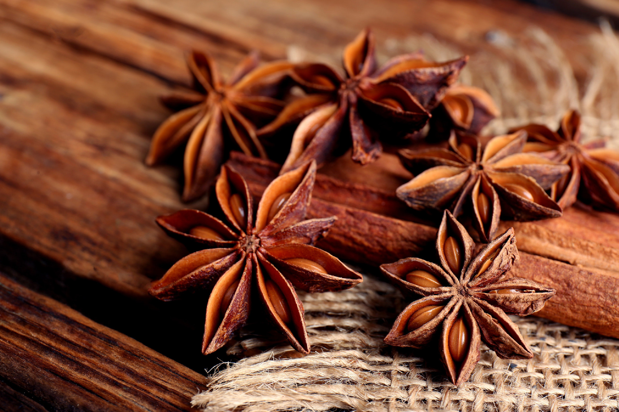 Aromatic anise stars and cinnamon sticks on wooden table, closeu