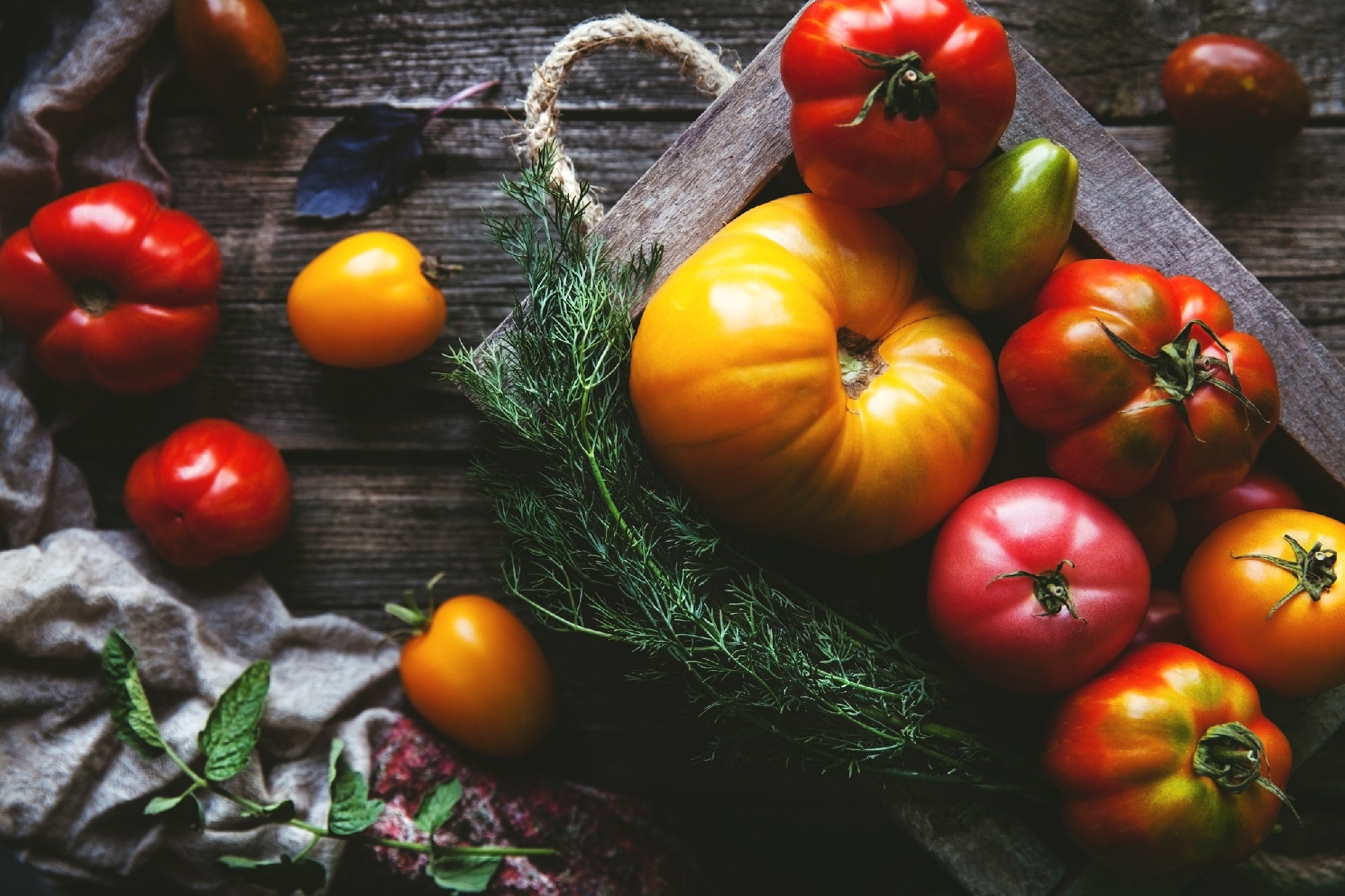Fresh tomatoes in an old box. On wooden background.