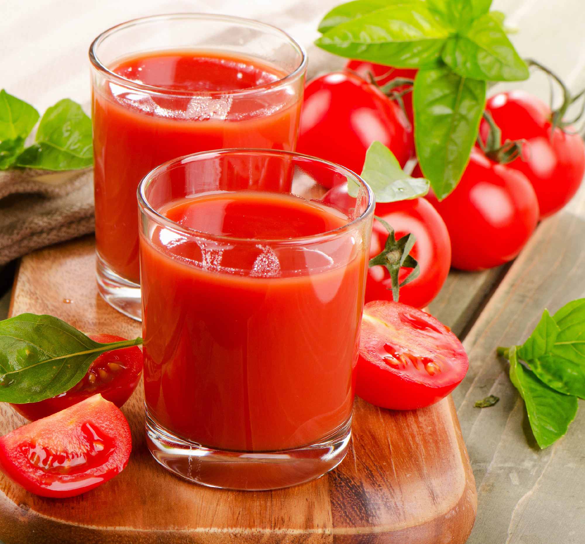 Tomato juice and fresh tomatoes on a wooden table