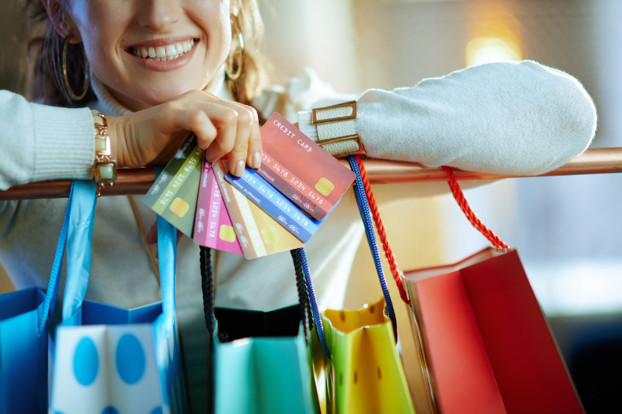 Closeup on woman near shopping bags with fan of credit cards