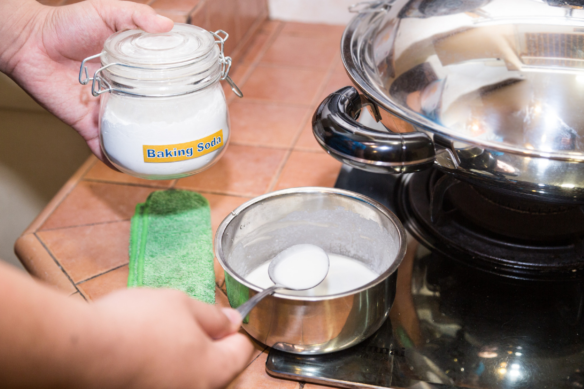Person holding spoonful mixed baking soda, effective natural cle
