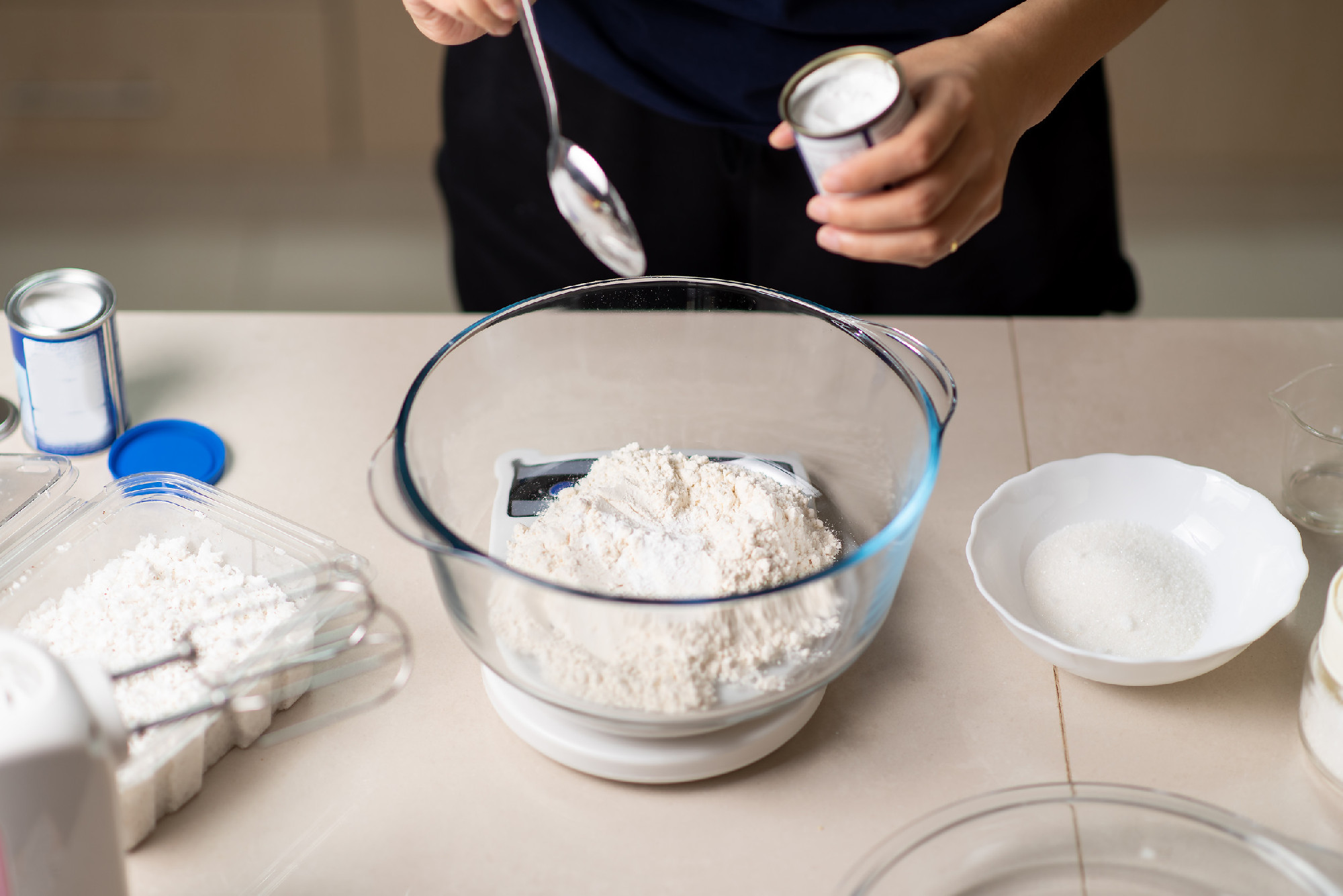 Woman adding bicarbonate soda to flour on a small kitchen scale 