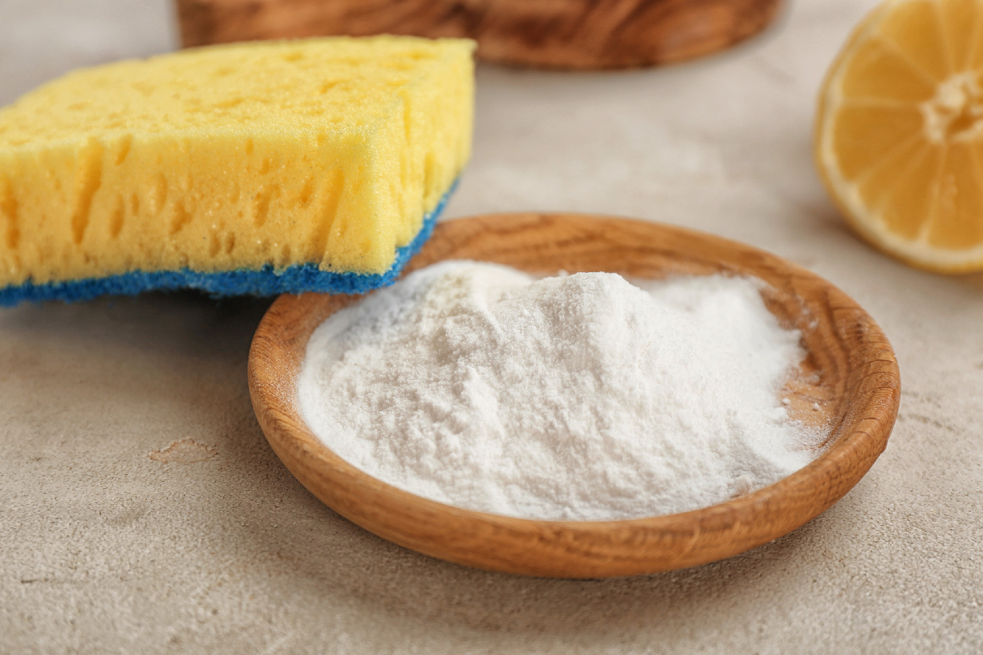 Bowl with baking soda and sponge on gray table�
