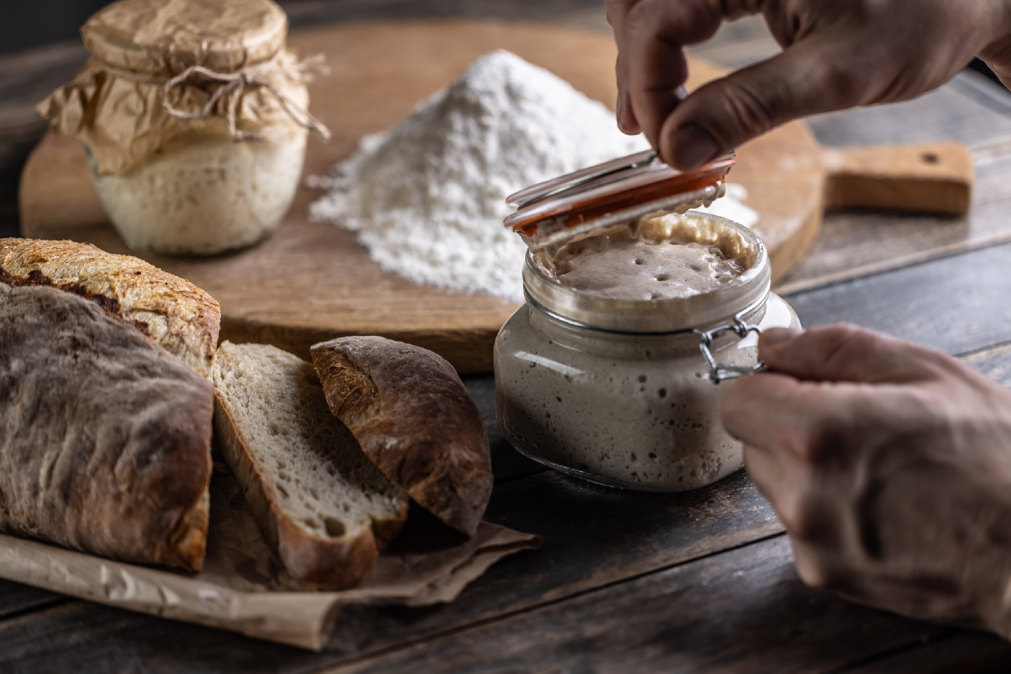 Male hands open a jar with active yeast, fresh bread and pastrie