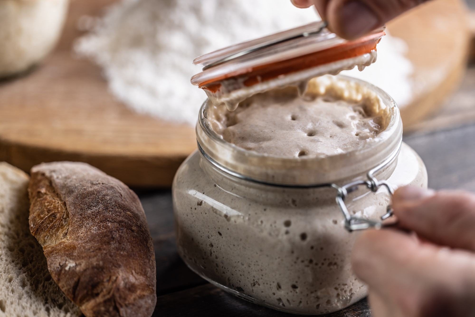 Male hands open a jar with active yeast, flour and fresh bread a