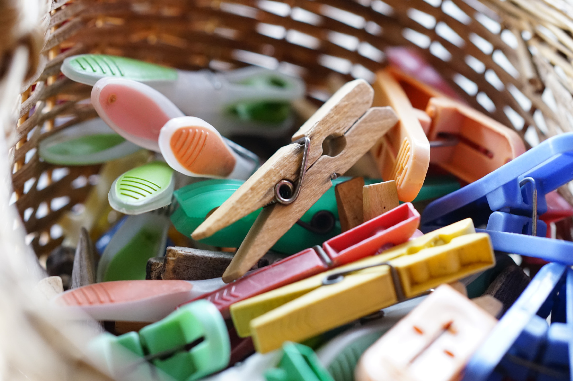 multi-colored wooden and plastic clothespins in a wicker basket