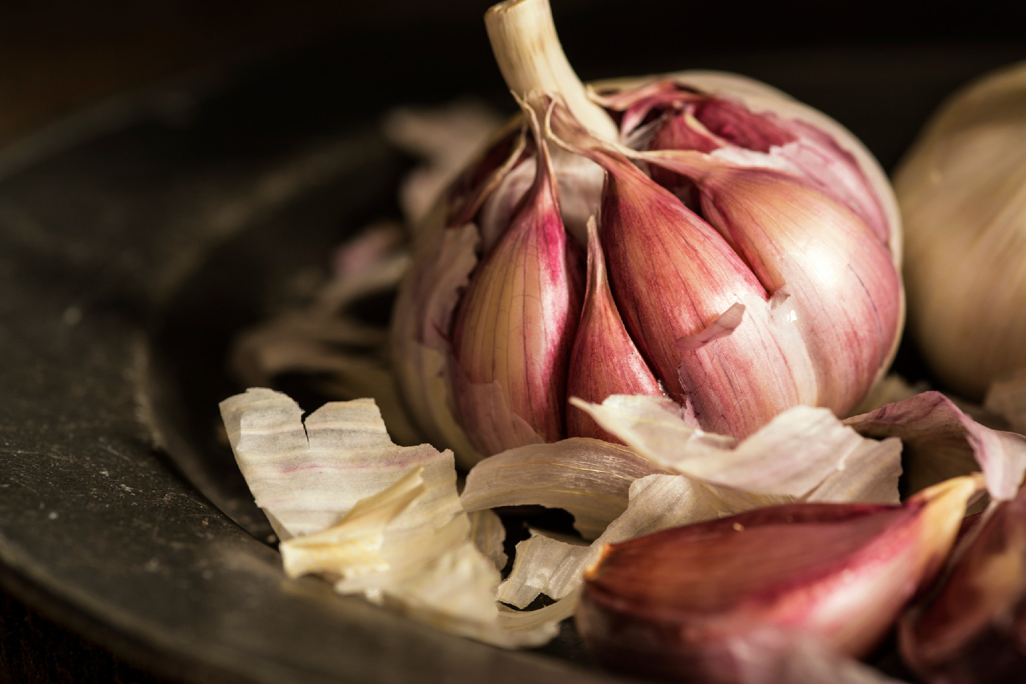 Fresh garlic cloves in moody natural lighting set up with vintag