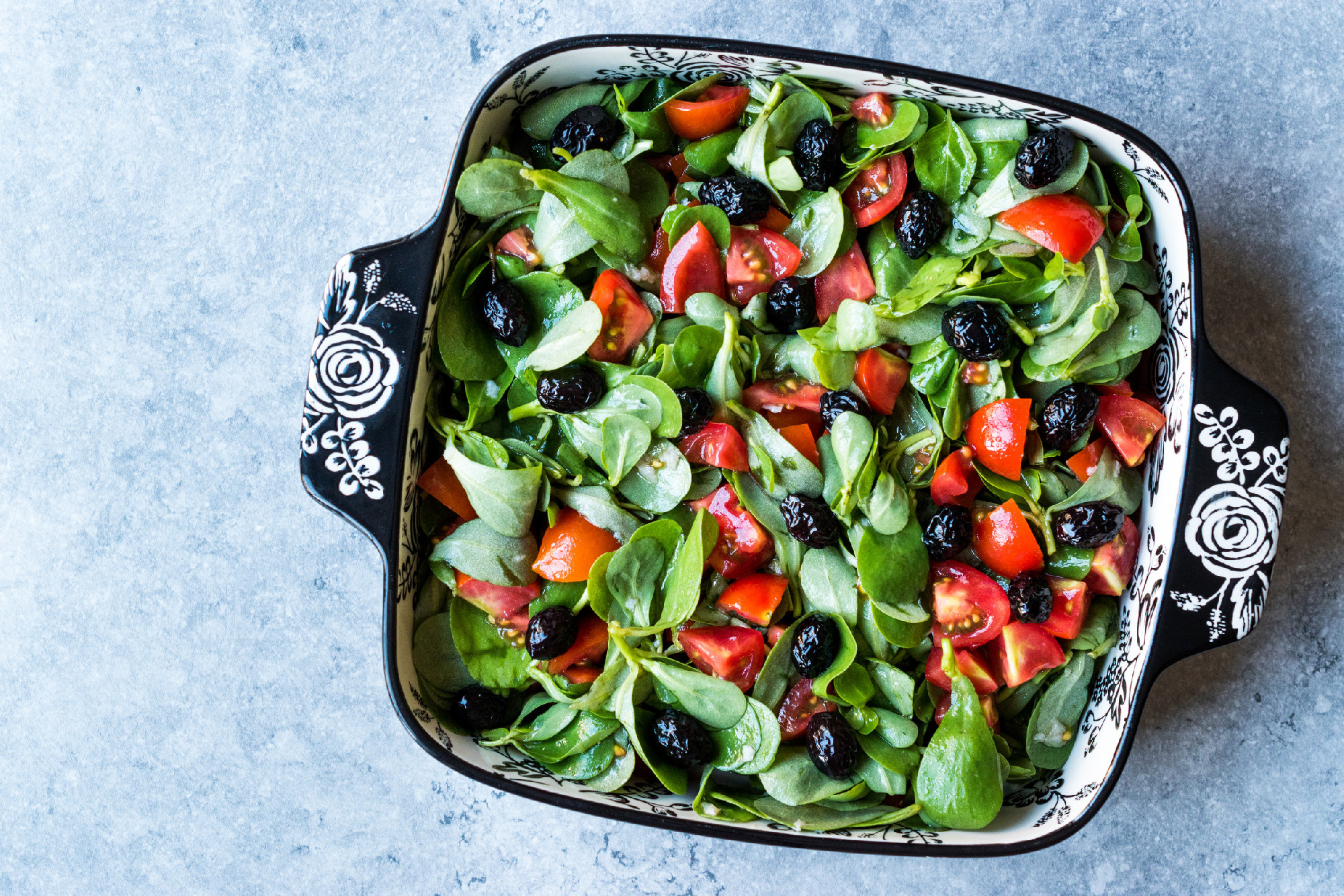 Purslane Salad with Tomatoes and Black Olives in Porcelain Bowl.