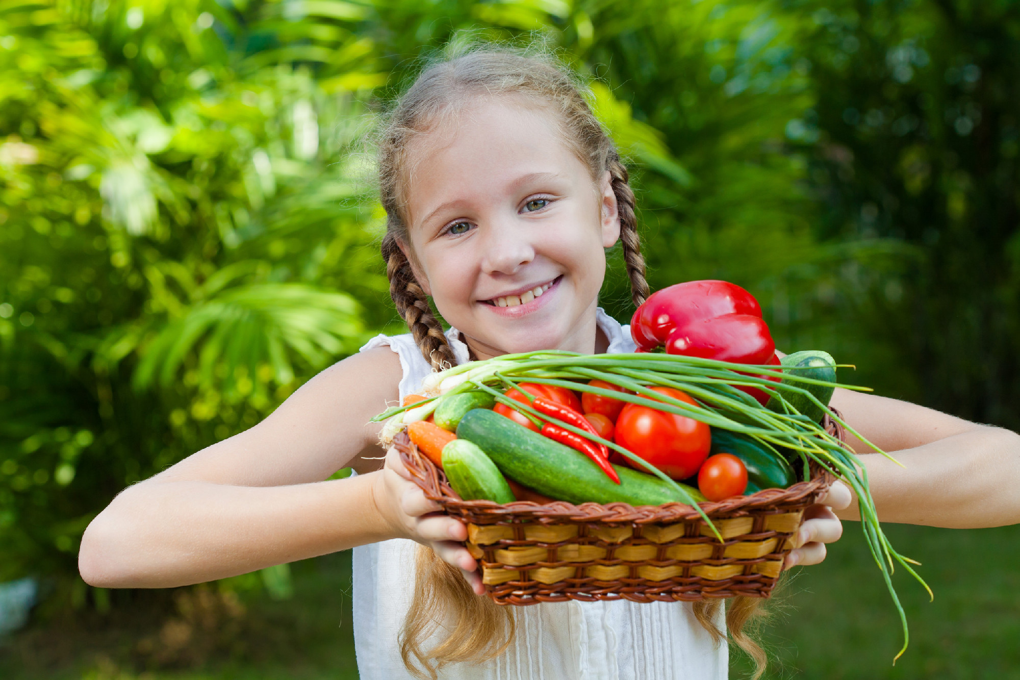 girl holding a basket of vegetables (cucumber, pepper, tomato, o
