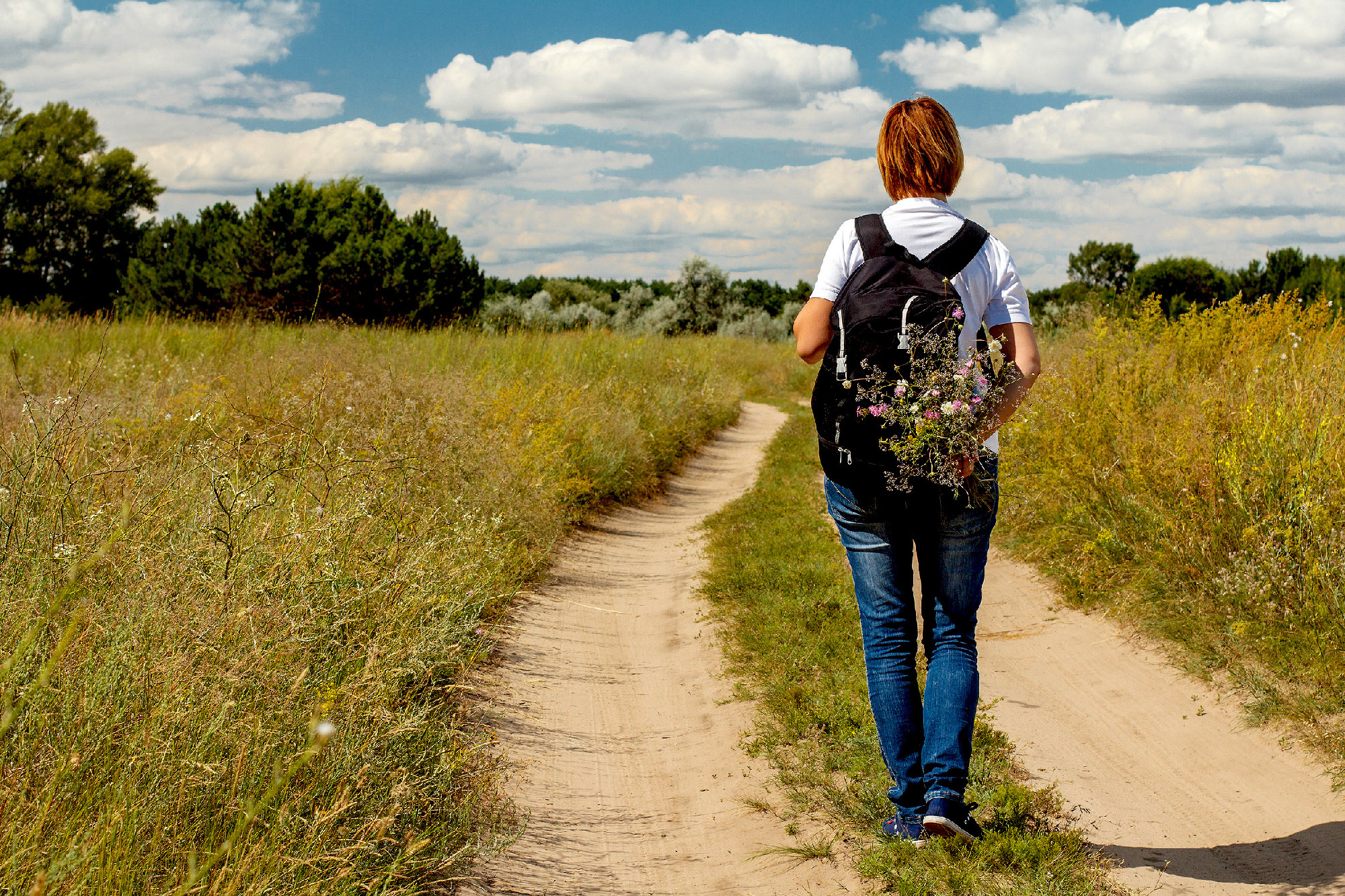 Hiker with backpack walking on rural road