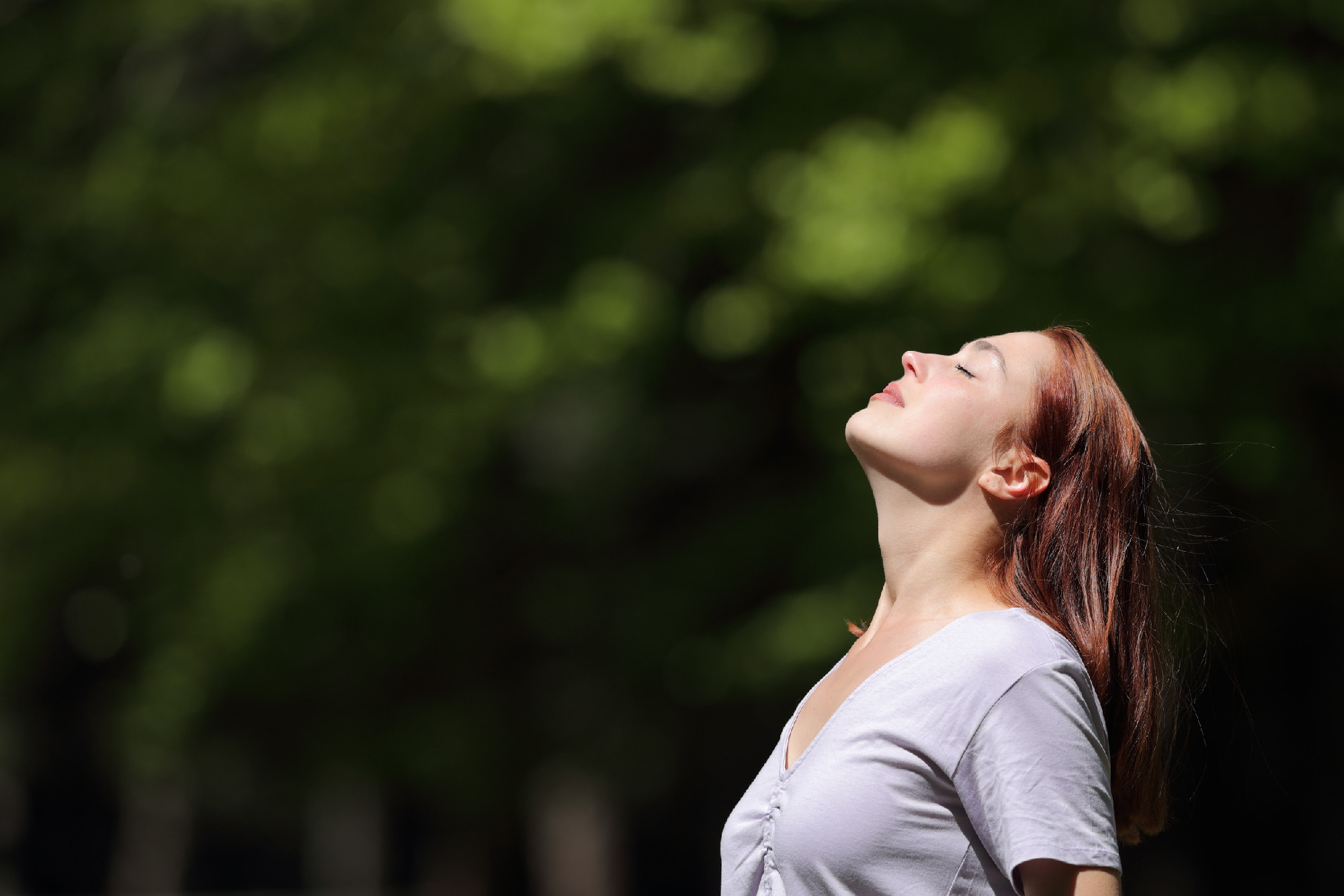 Woman breathing and heating under sun in a park