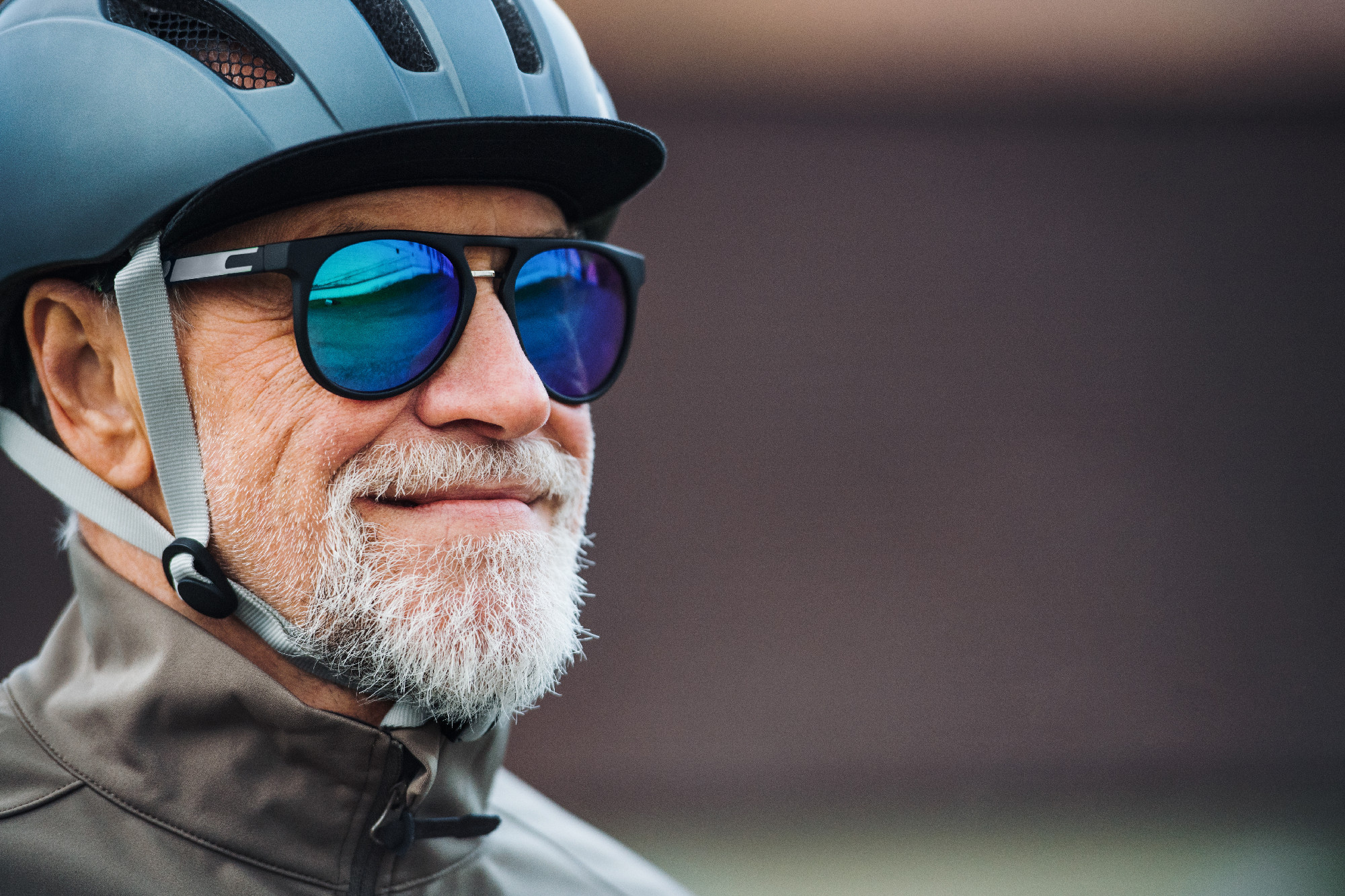 Close-up of active senior man with sunglasses and helmet standing outdoors. Copy space.