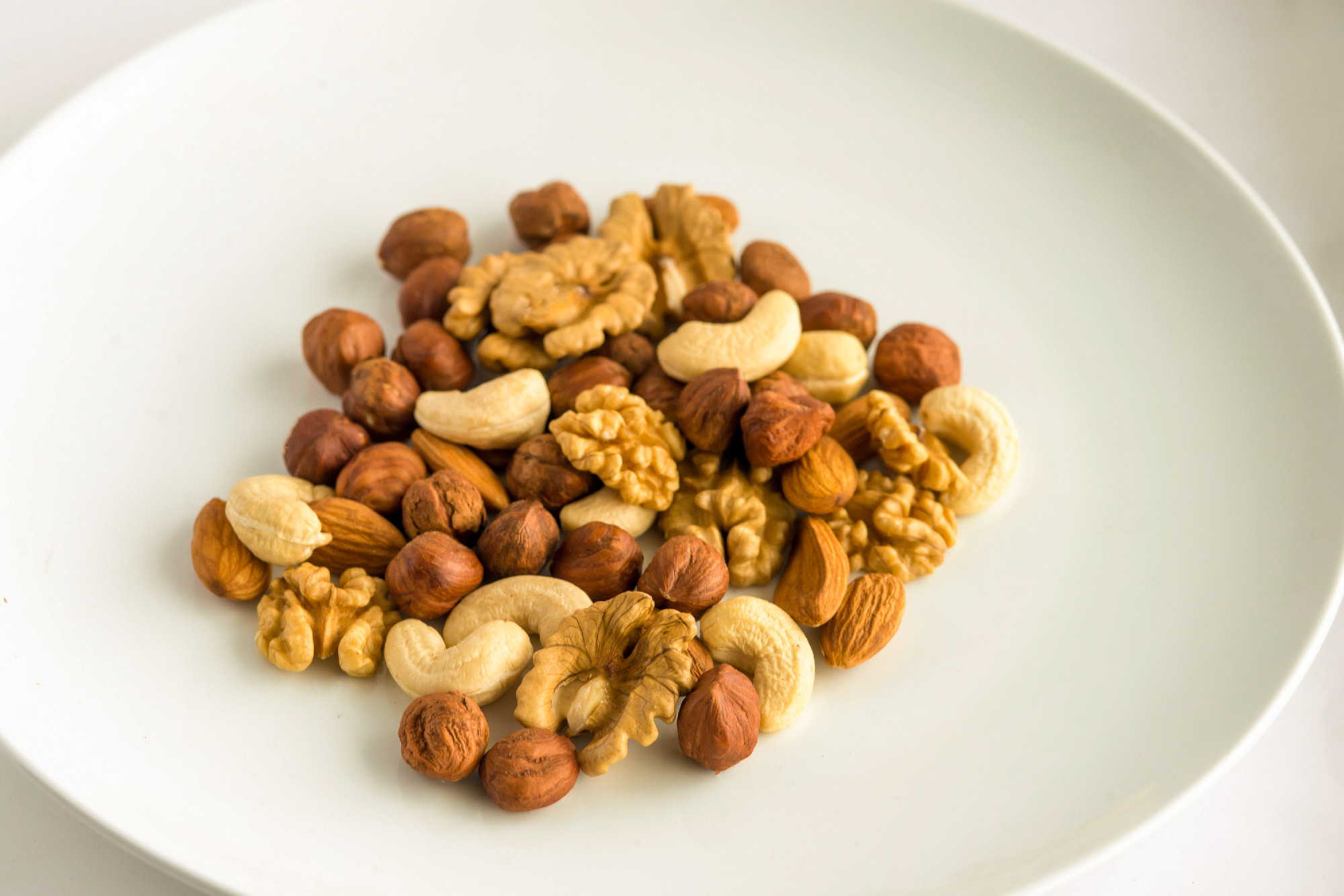 Mixed nuts in plate on white background.