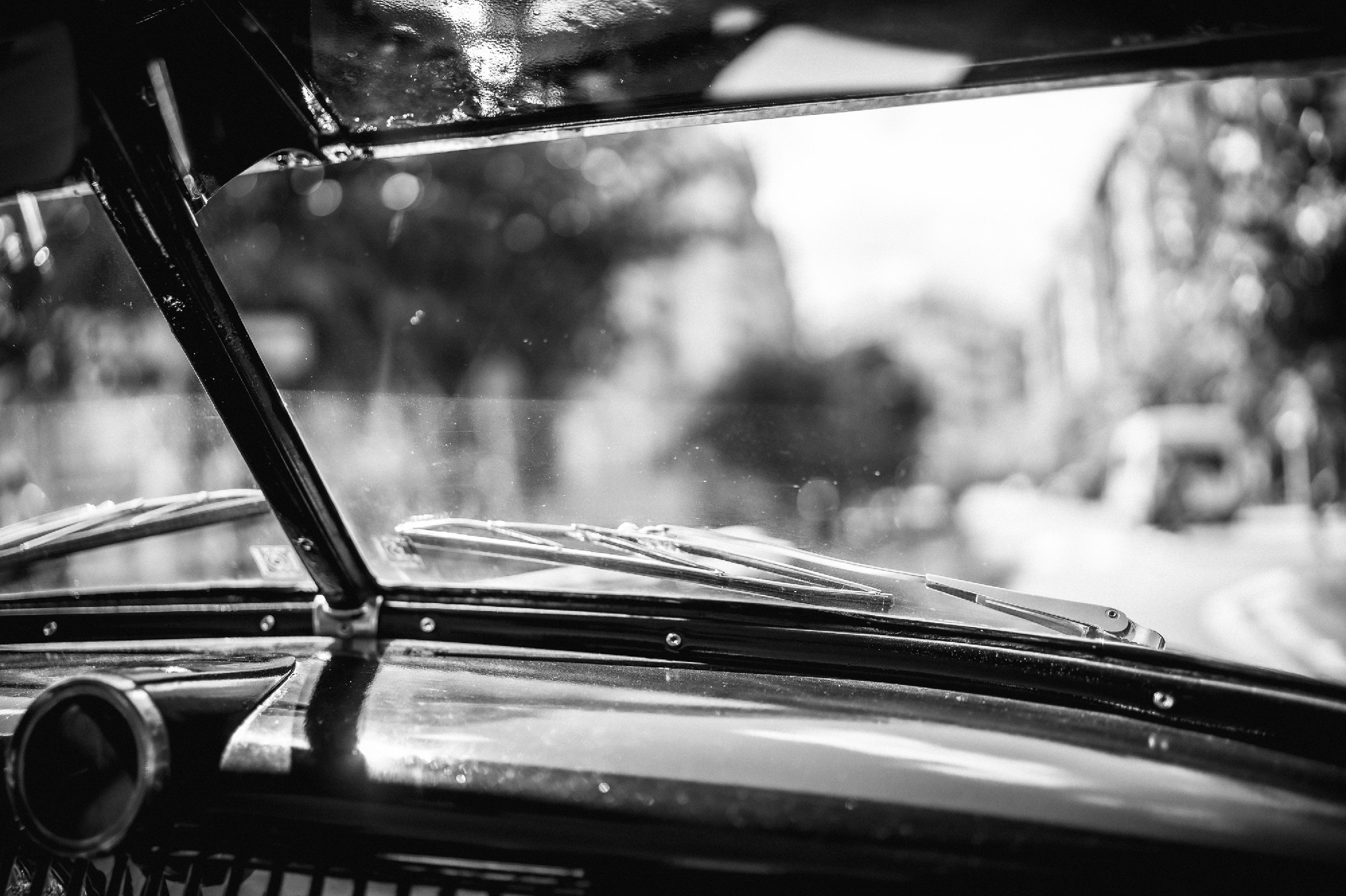 A black and white photo of a car window with a city in the backg