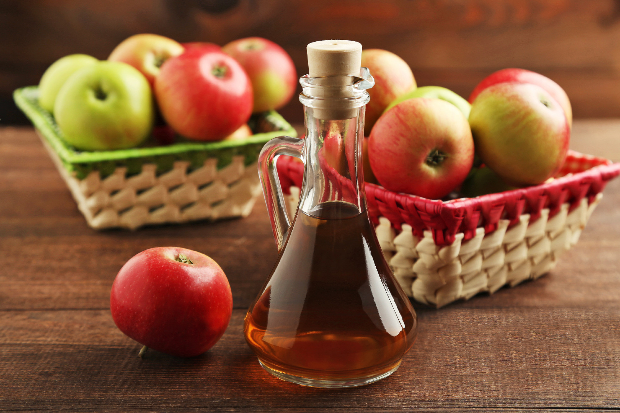Apple vinegar in glass bottle on brown wooden table
