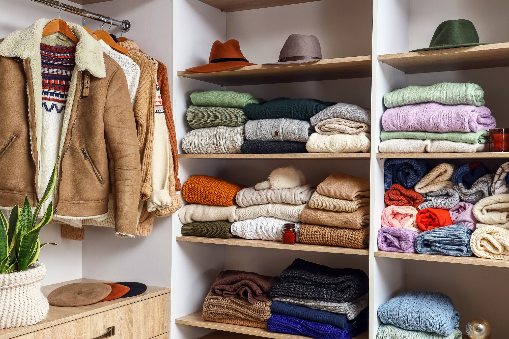 Shelves with warm sweaters and hats in wardrobe