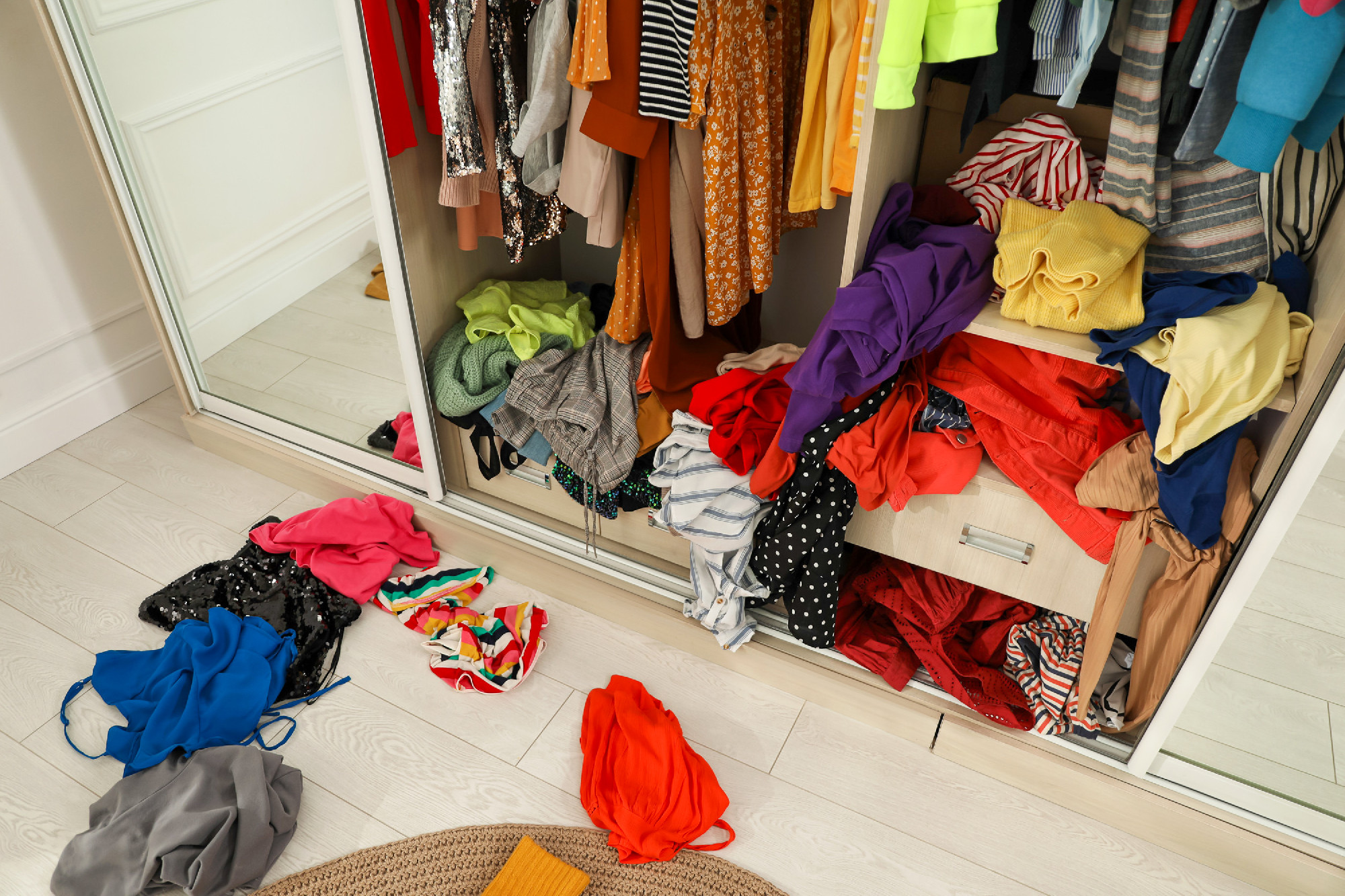 Messy wardrobe with different clothes indoors. Fast fashion conc