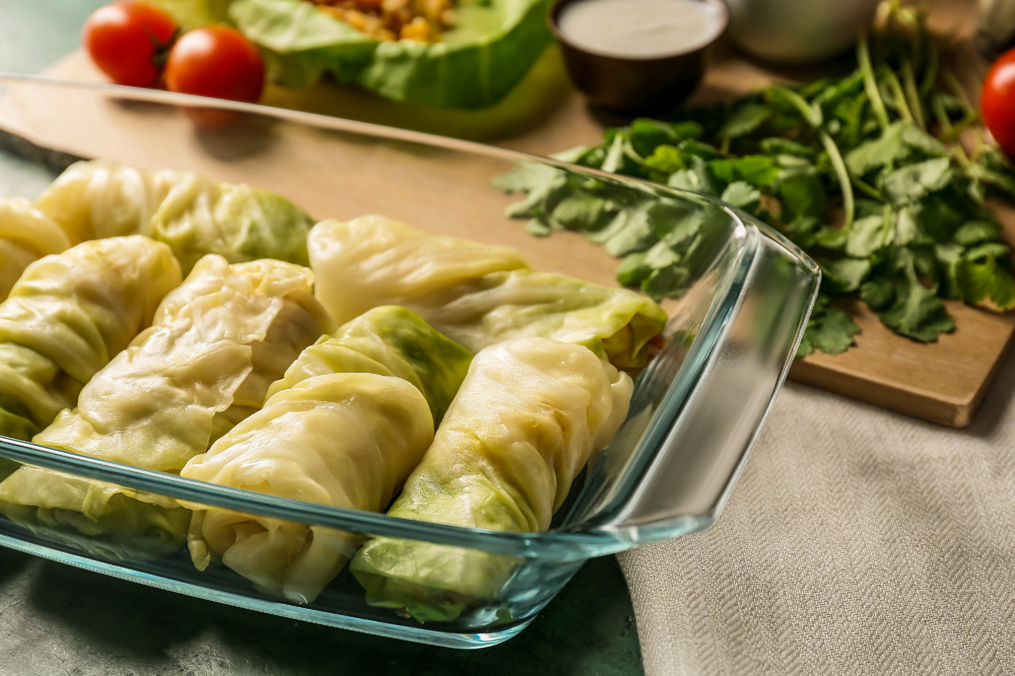 Baking dish with uncooked cabbage rolls on table