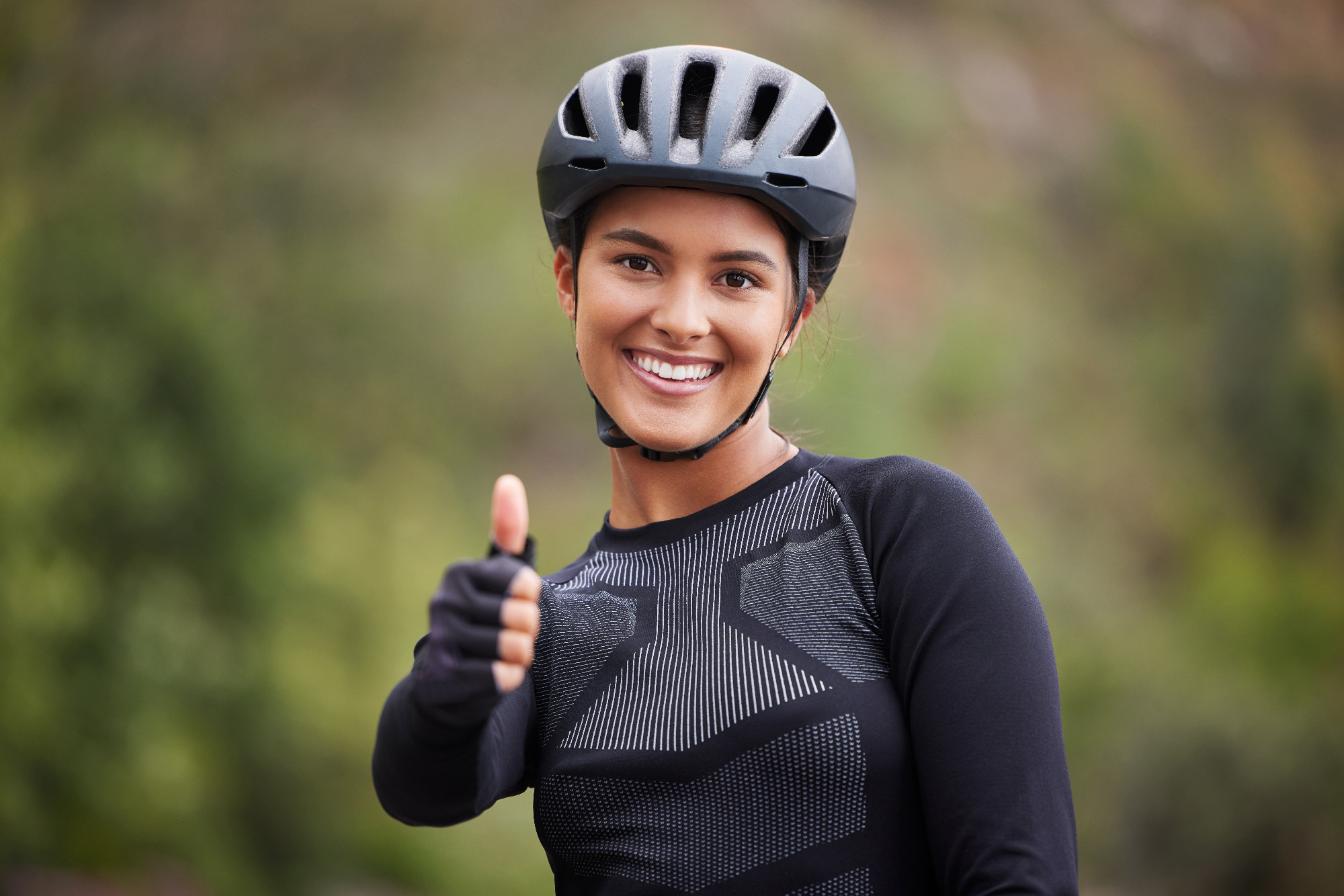 Sports, thumbs up and portrait of woman with helmet in nature for training, workout and exercise. Fitness, cycling and happy person with emoji, gesture and sign for adventure, wellness and marathon