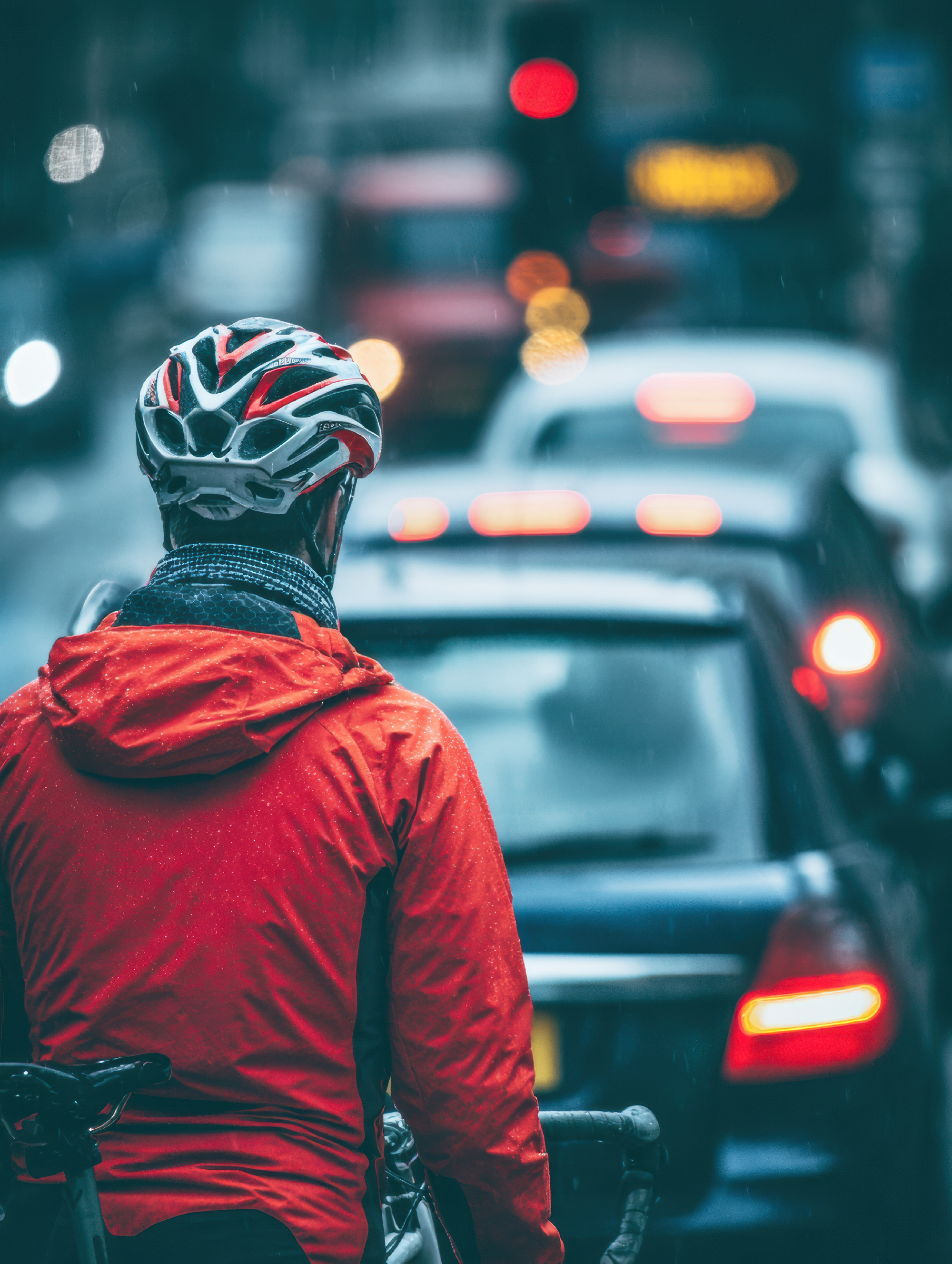 Cyclist Waiting in Traffic on a Rainy Day in a Bustling City