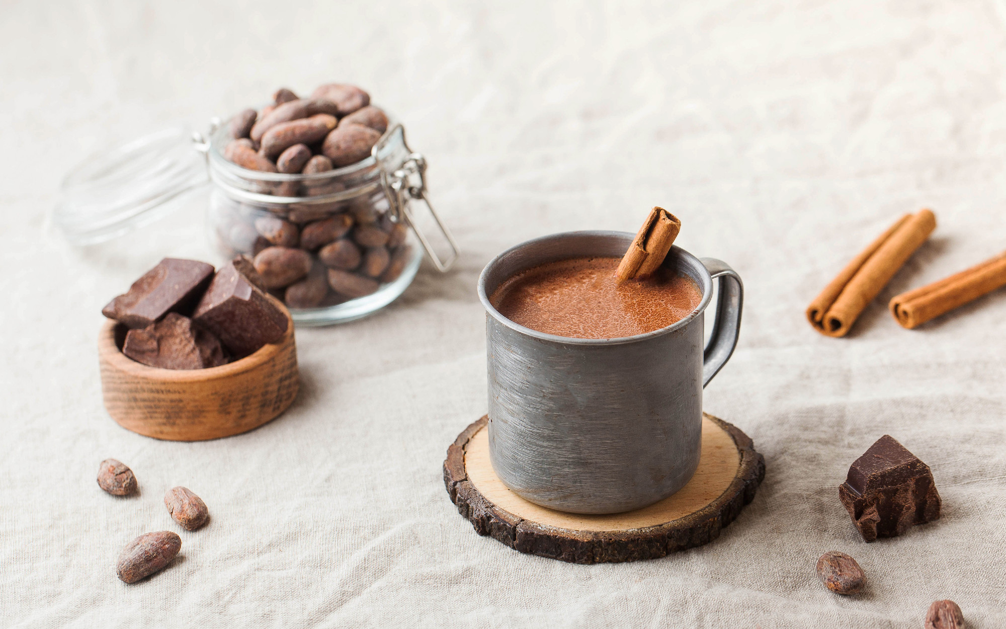 Hot chocolate in a metal mug with a cinnamon stick on the tablec