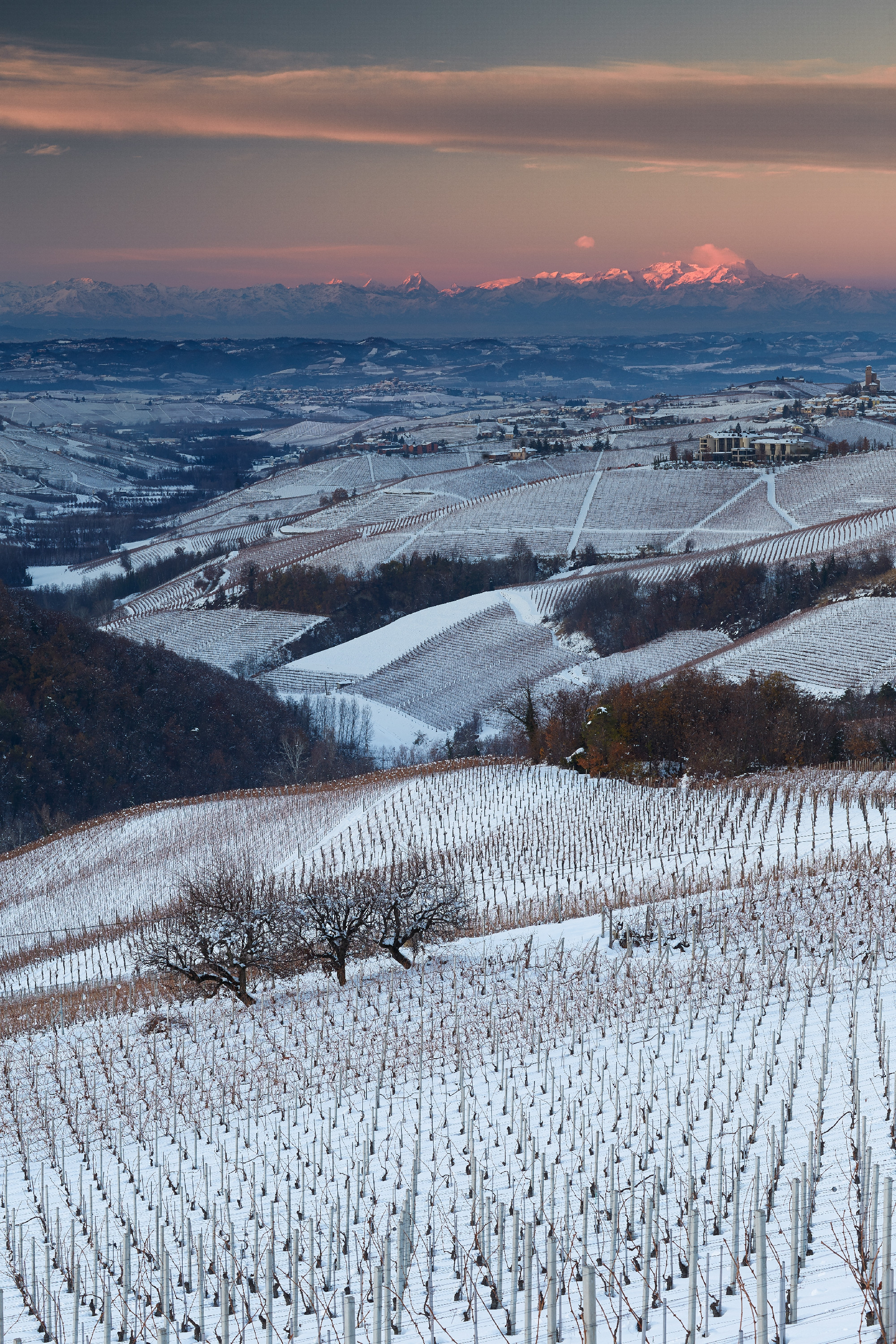Vertical shot of fields covered in the snow surrounded by hills on the countryside