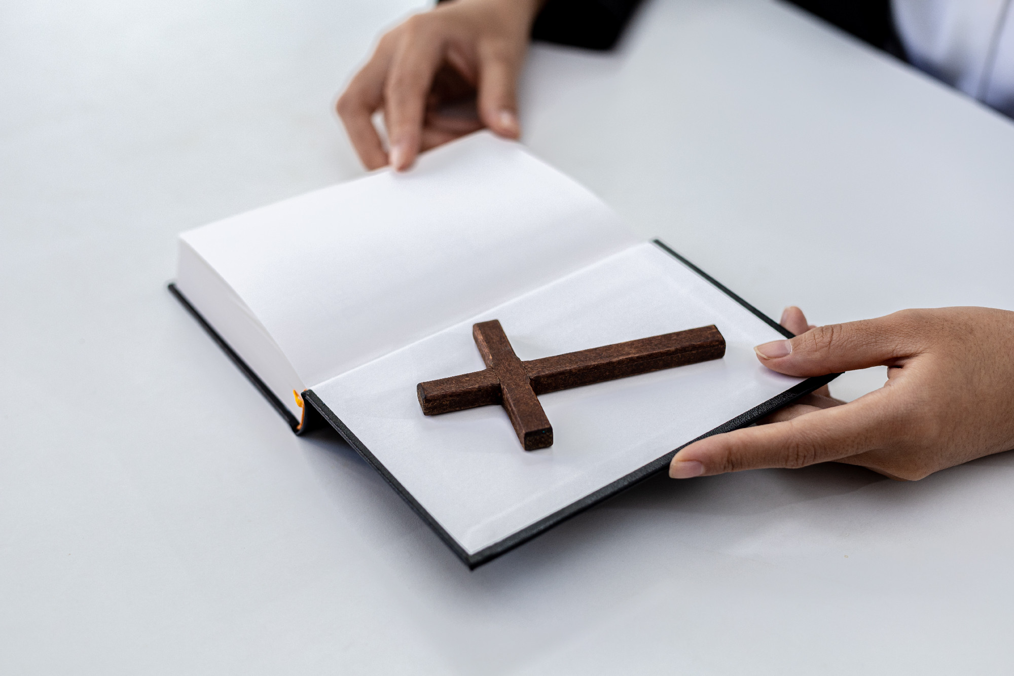 A person is reading the Bible and a cross is placed, he is prayi