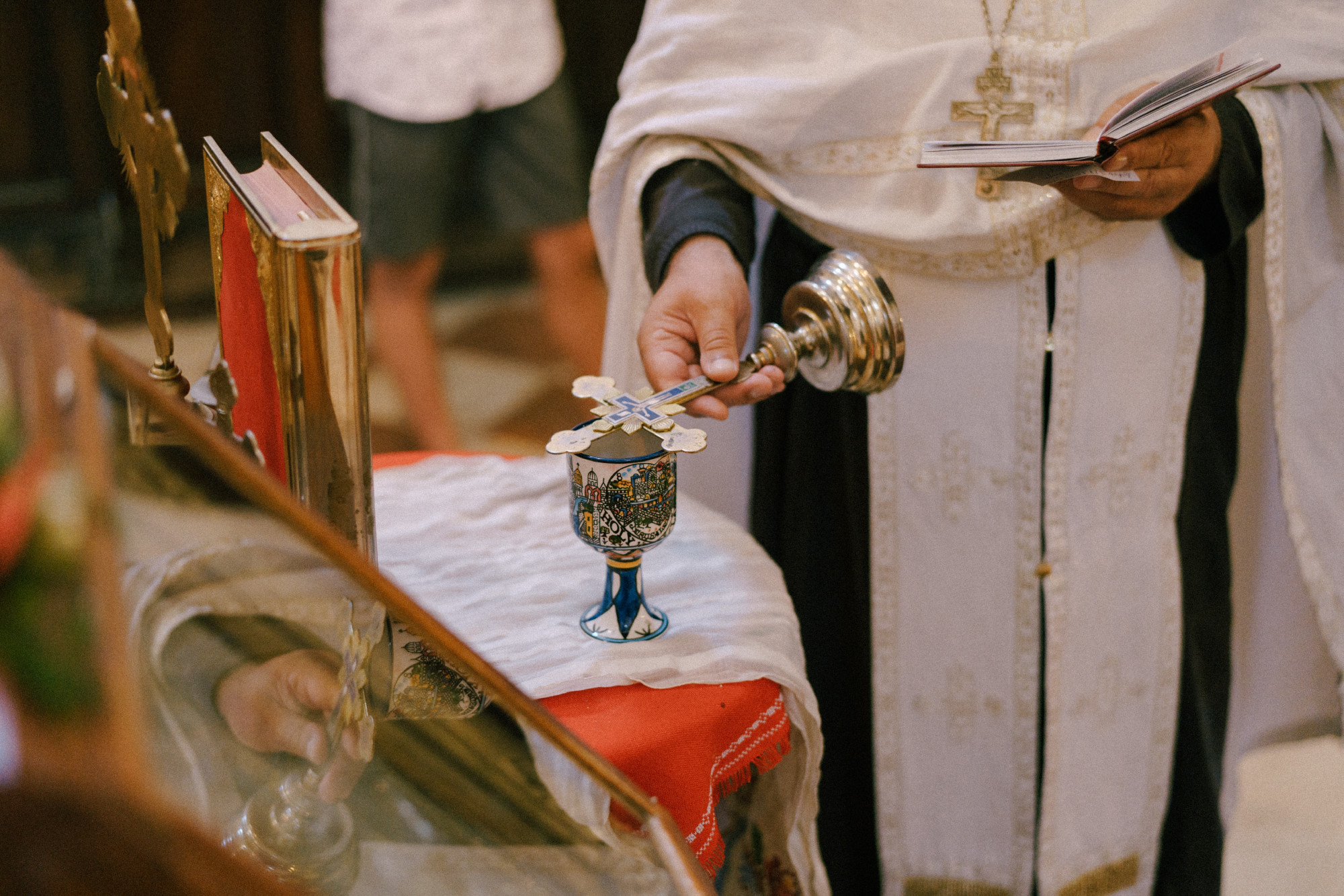 Priest presides over the service, holding the Bible and the cross in his hand