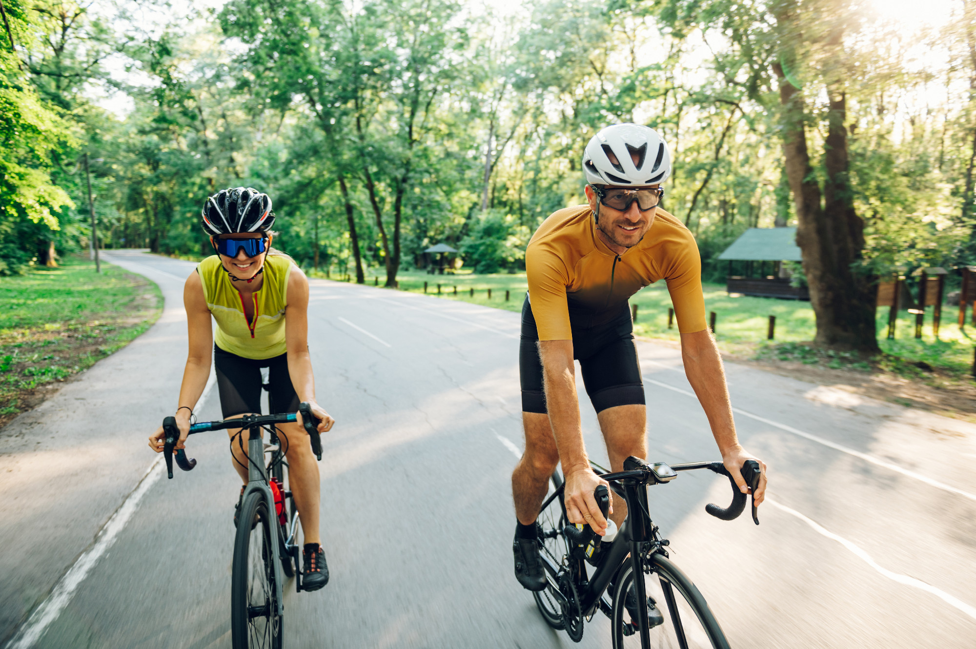 Couple riding road bicycles outside and wearing helmets and sung