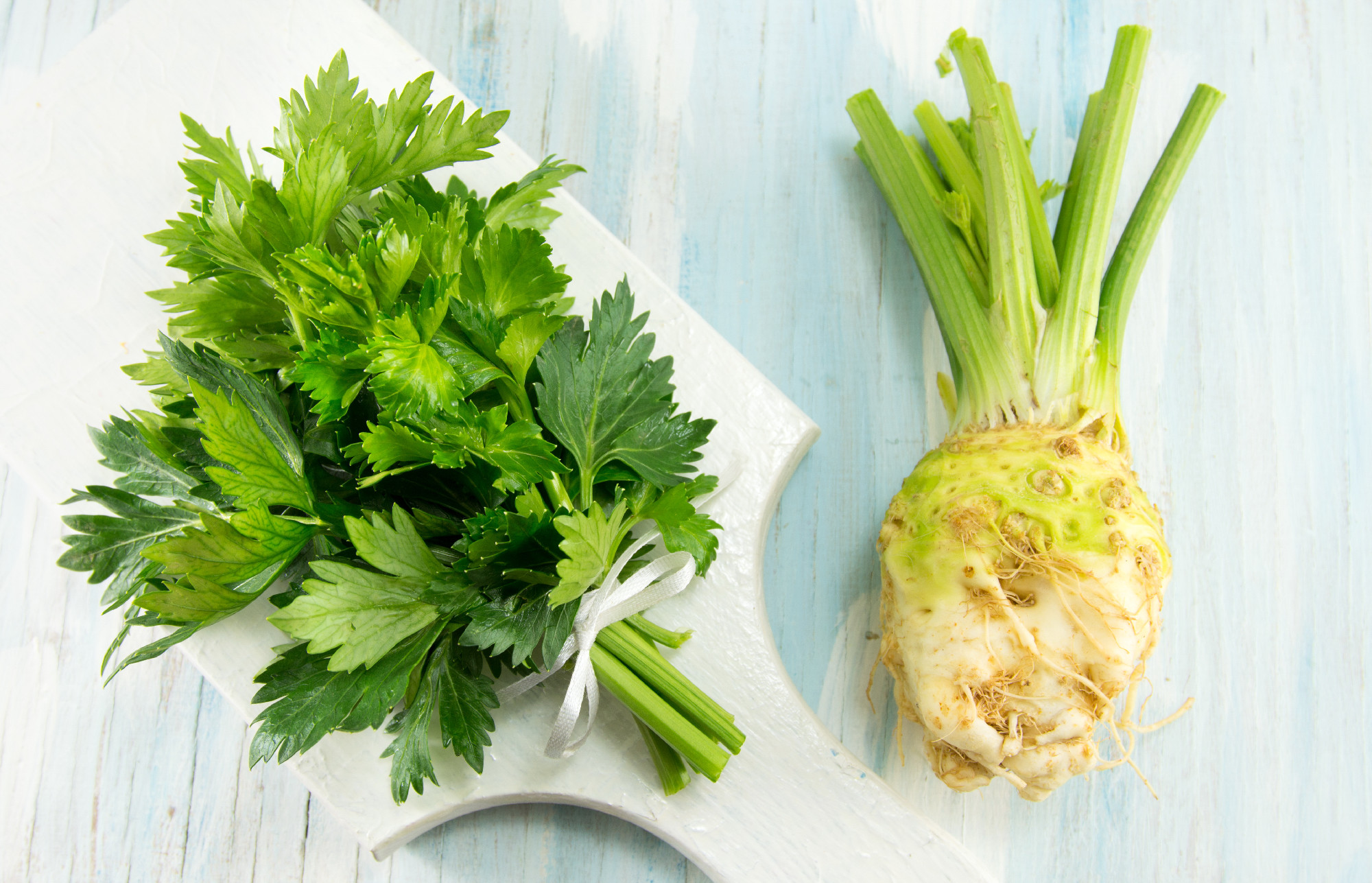whole celery on a white cutting board