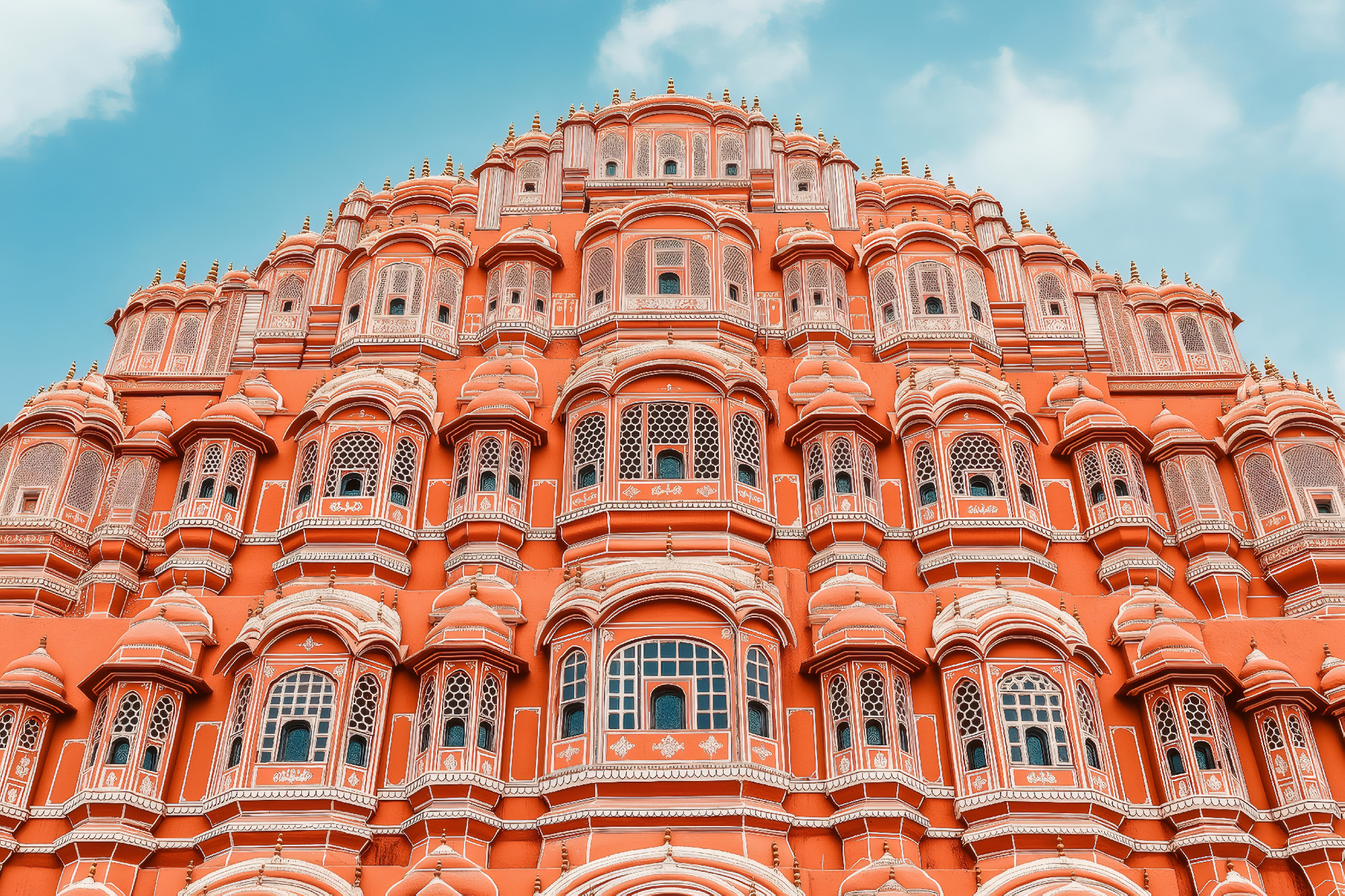 Stunning facade of Hawa Mahal, Palace of Winds, a historic landmark in Jaipur, India, showcasing intricate carvings and vibrant colors against a clear blue sky