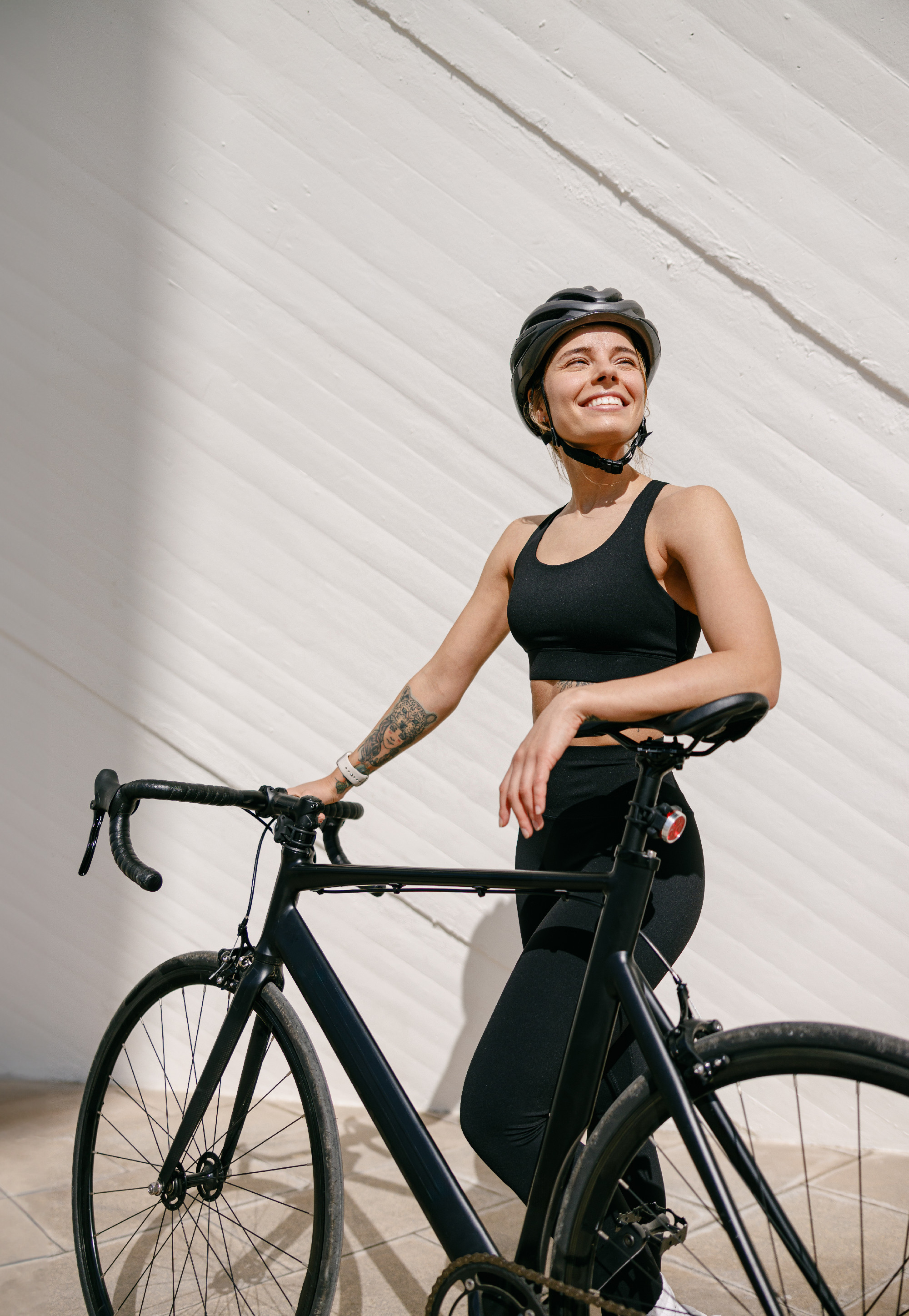 Woman cyclist in protective gear standing with her bike while training outdoors and looks away