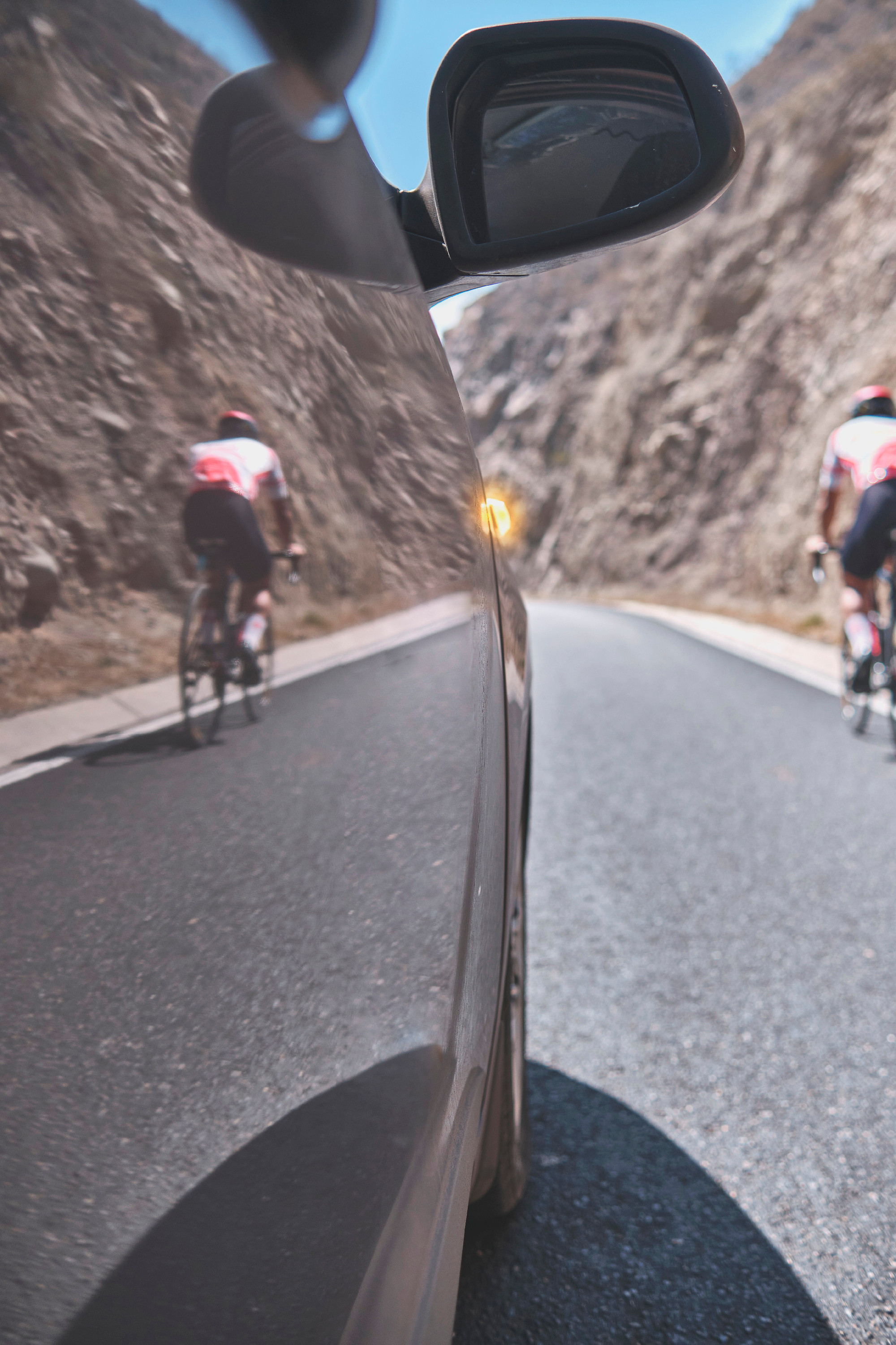 Professional cyclist training on the road with safety escort car. Cyclist followed by team car.