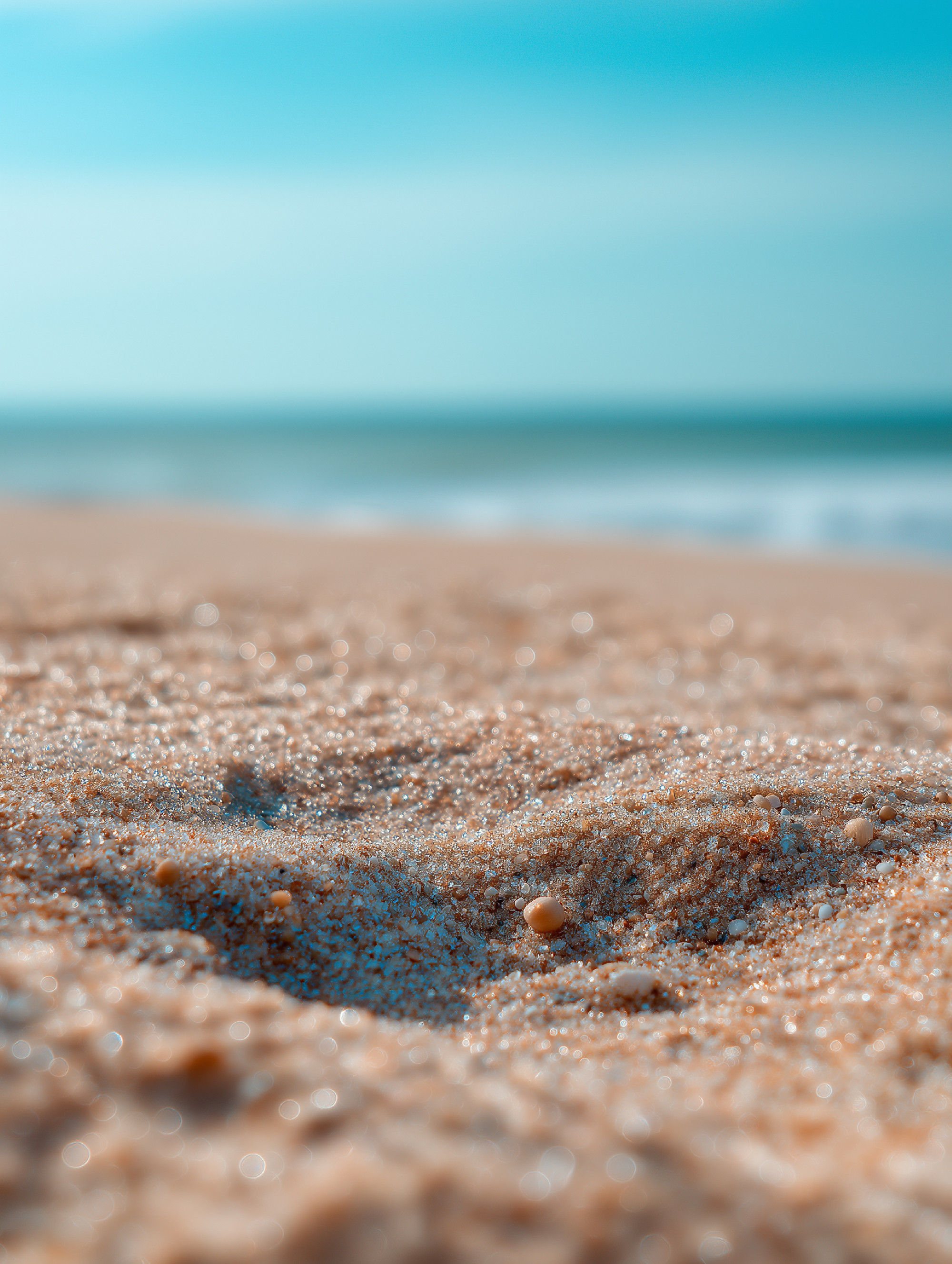 Sunlight warms a sandy beach, casting a golden glow as gentle wa