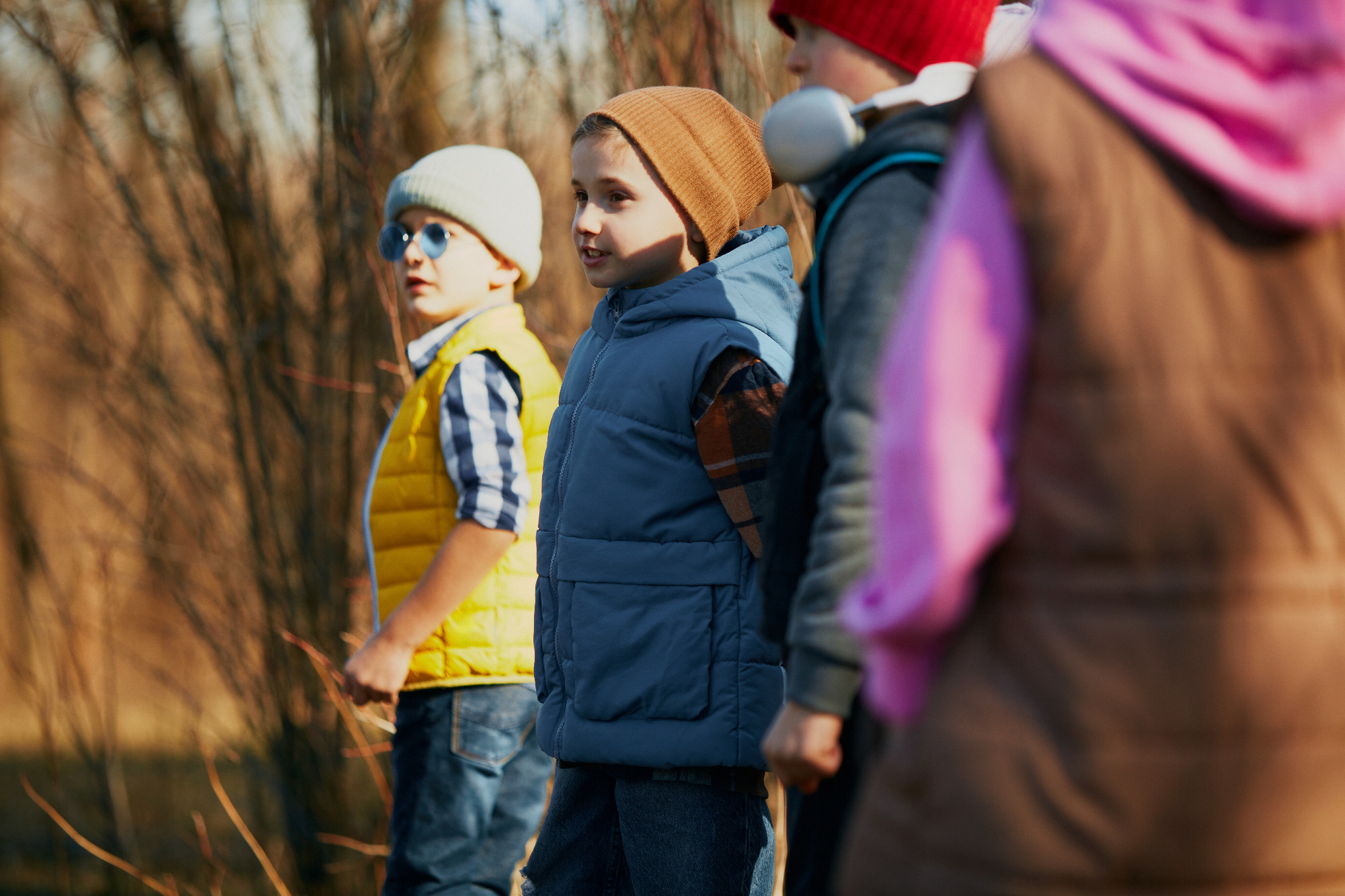 Curious kids, classmates, in warm attire observing something interesting in nature. Outdoor activities for children's development.