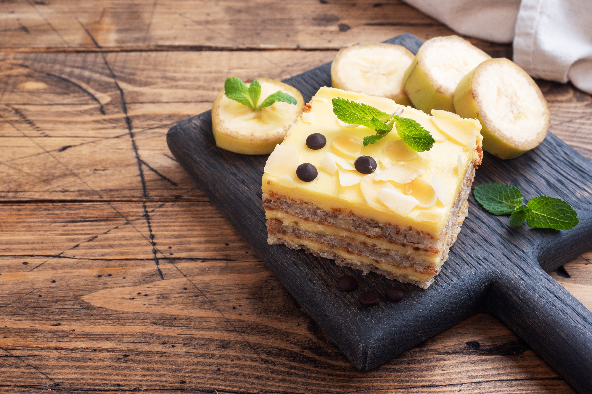 Banana sponge cake with nuts and chocolate drops. Delicious sweet dessert for tea, wooden background. top view, copy space.