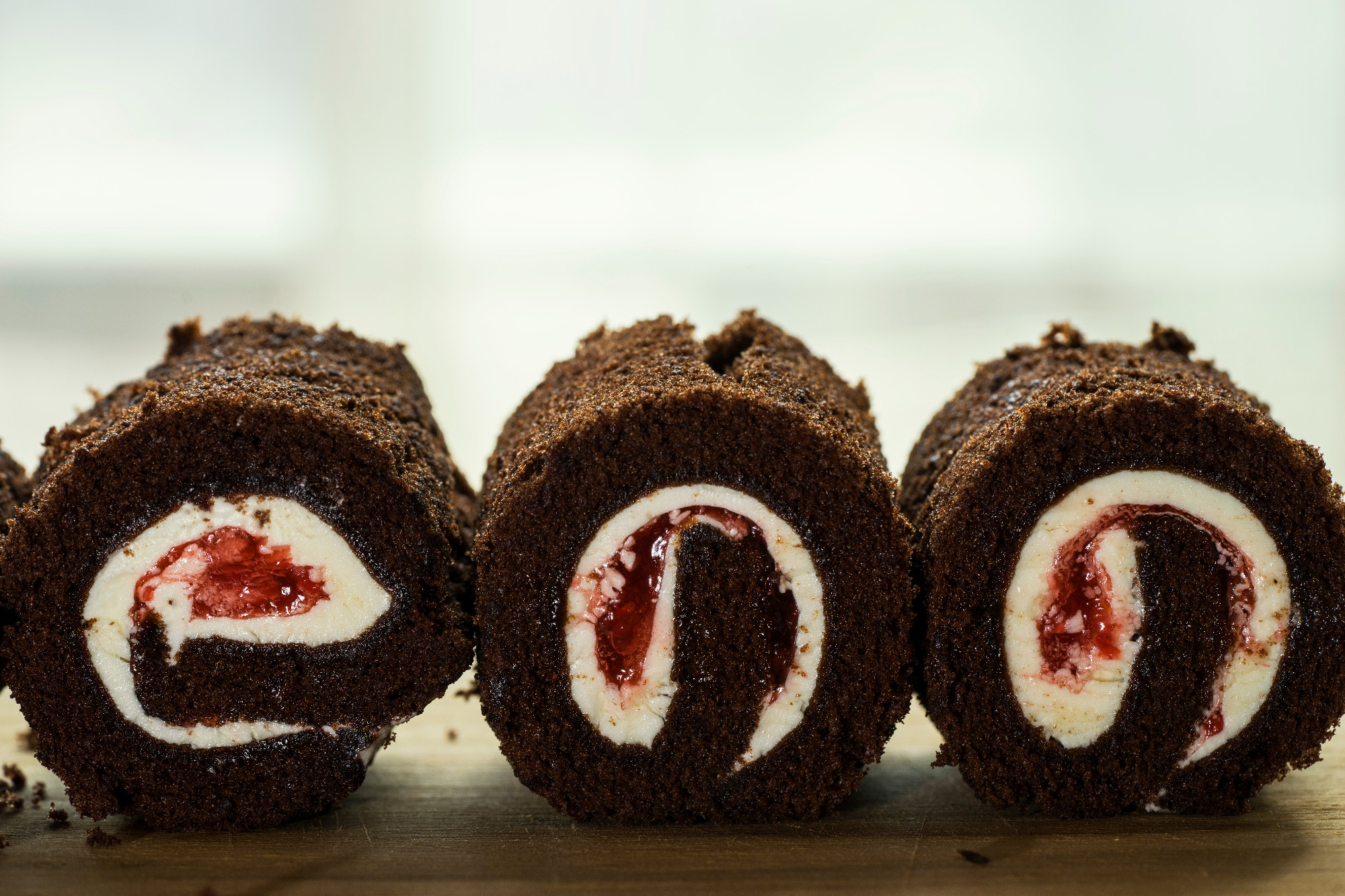 three black forest cake roll face cut on wood
