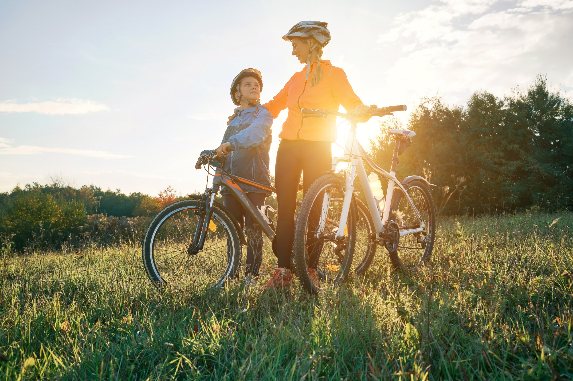 Mother and son ride a bike. Happy cute boy in helmet learn to ri