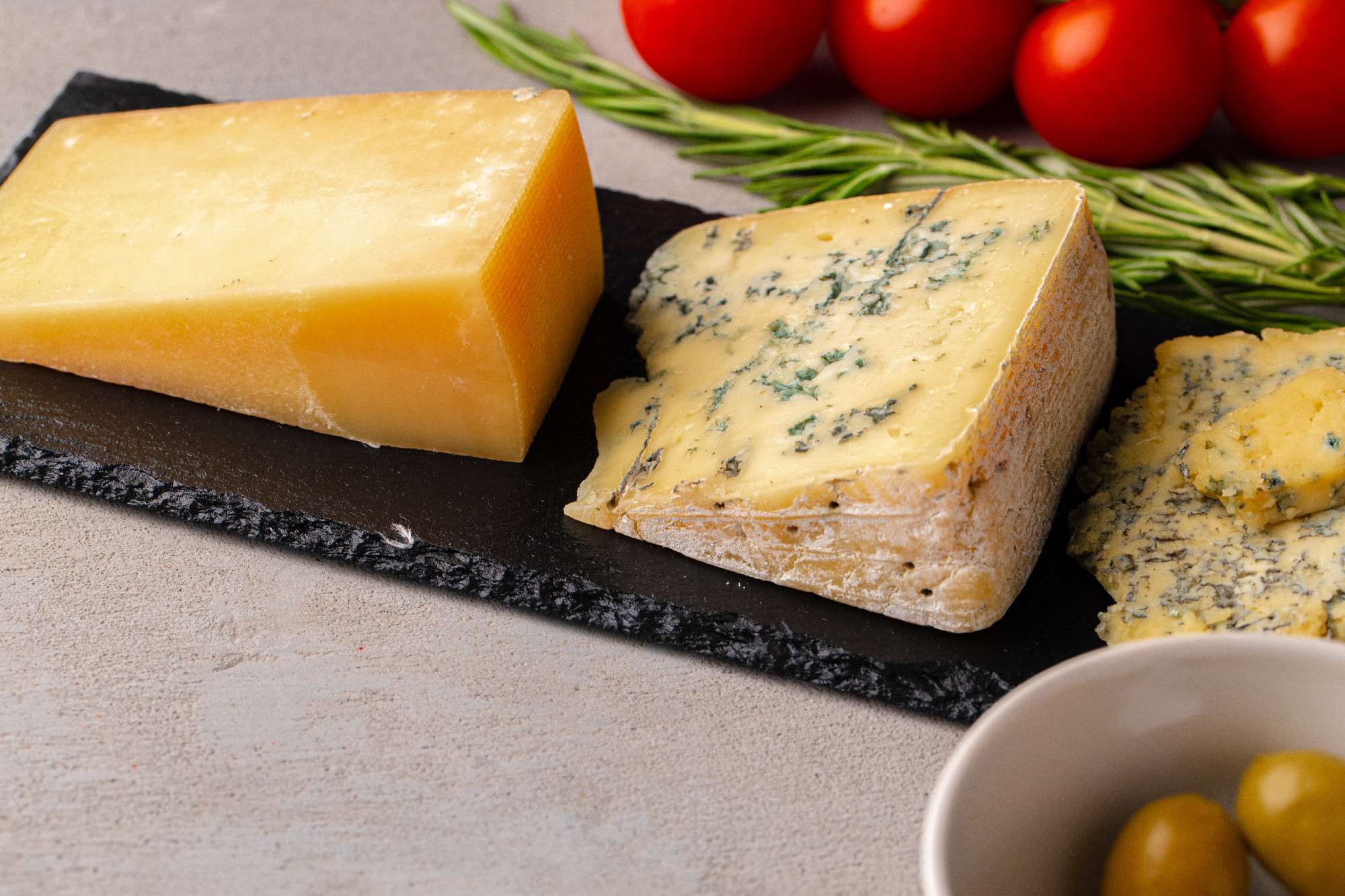 Several different pieces of cheese served on black stone flat plate