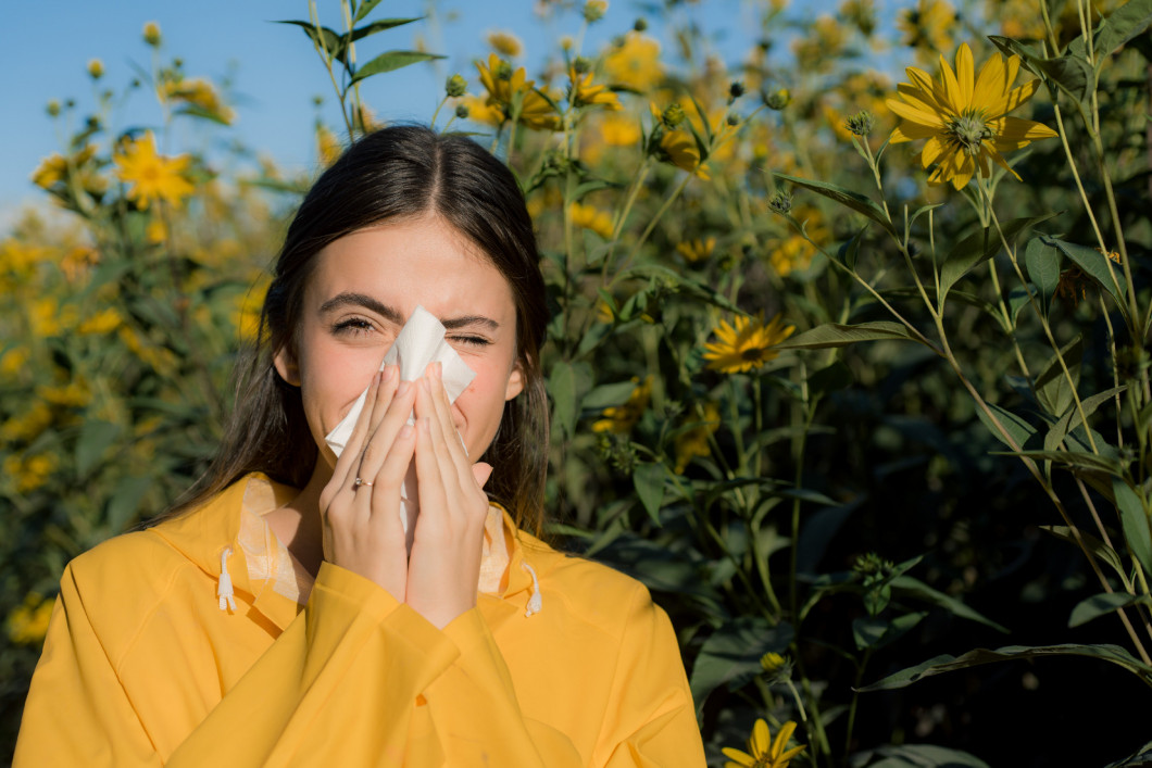 Beautiful sexy young woman lies on flowers background. Young woman got nose allergy, flu sneezing nose. Pretty woman got flu sneezing nose. Flu.