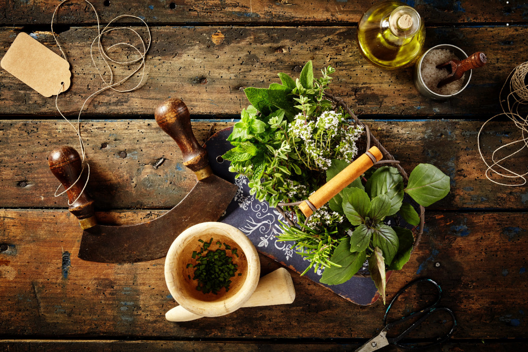 Herbs, oil and mezzaluna over old wooden table