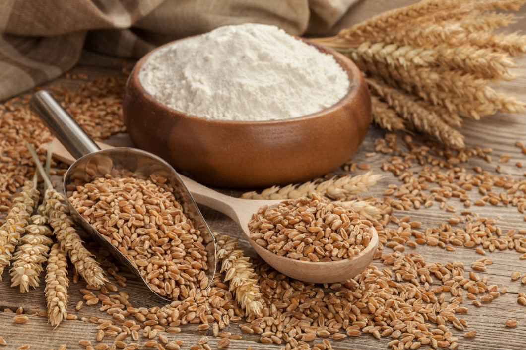 Ears of wheat and flour in the wooden spoon on board. Easter concept
